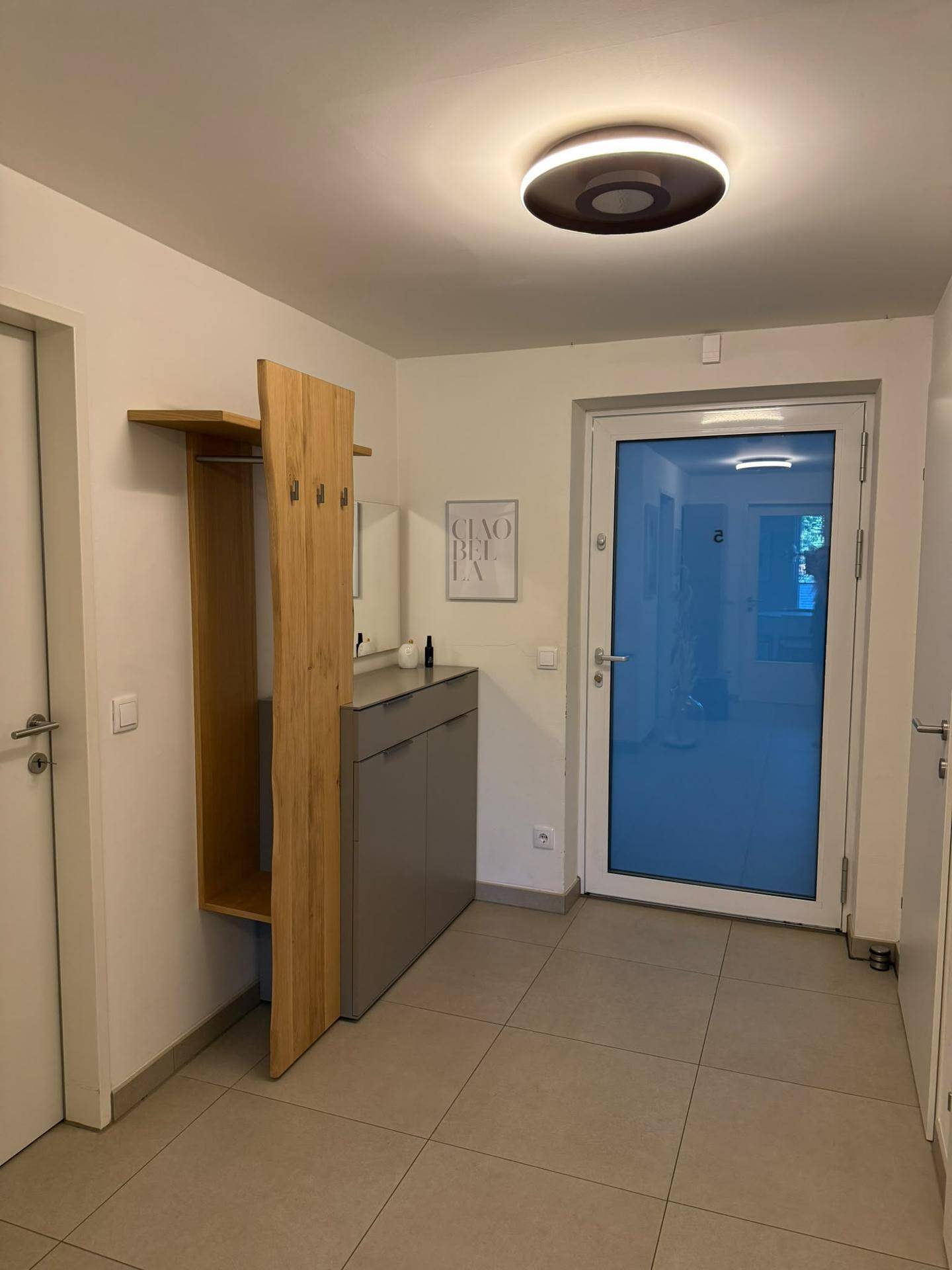 Moderner Eingangsbereich mit Holzgarderobe, Schuhschrank und Fliesenboden.