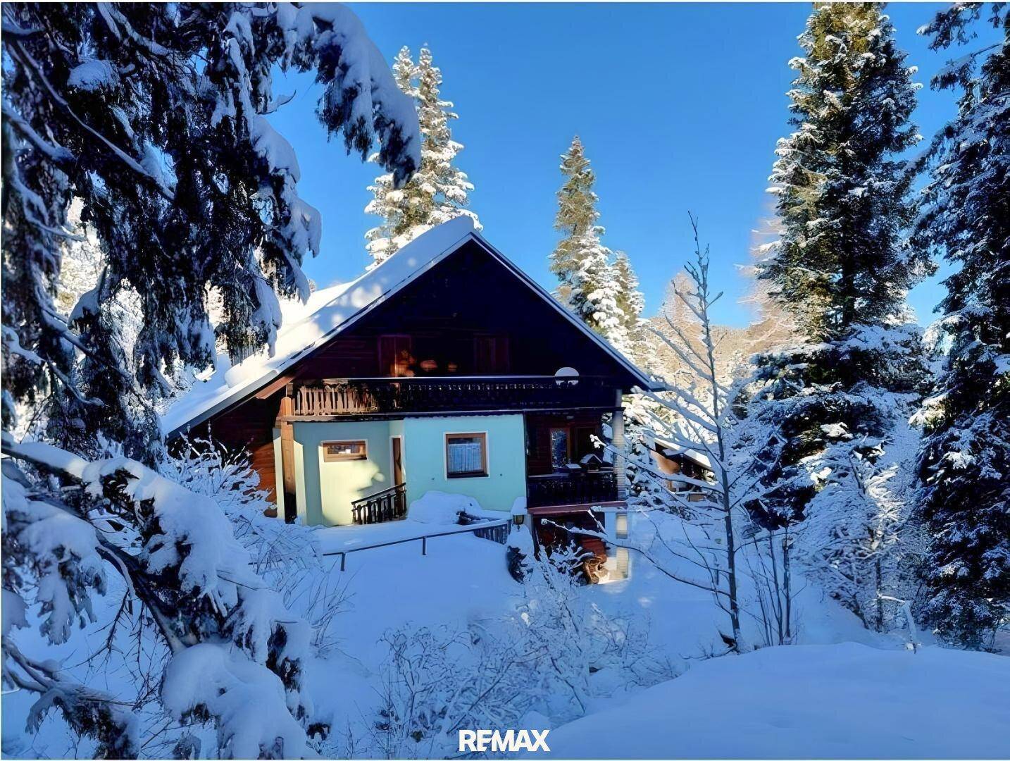 Winterliche Ansicht des Hauses mit tiefem Schnee und klarem blauen Himmel.