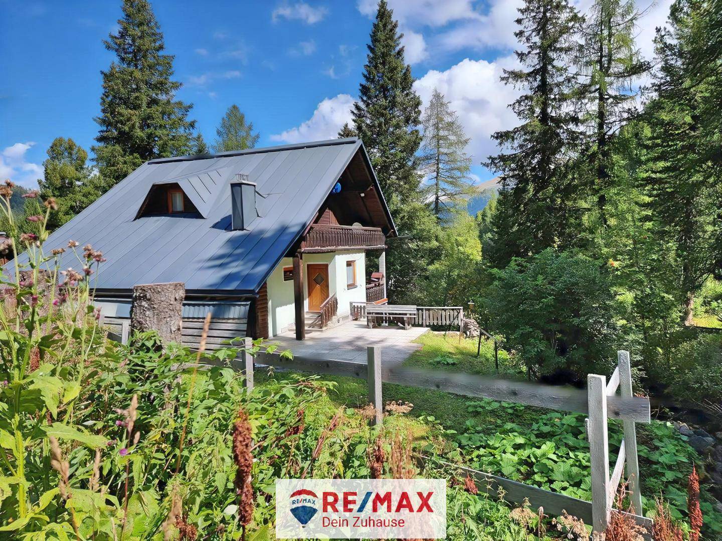 Charmantes Chalet mit Terrasse und Gartenbereich, umgeben von üppiger Natur und einer malerischen Bergkulisse.