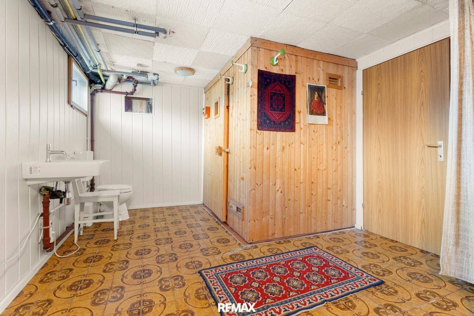 Kellerraum mit integrierter Sauna, Waschbecken und Toilette, ideal für Wellness.