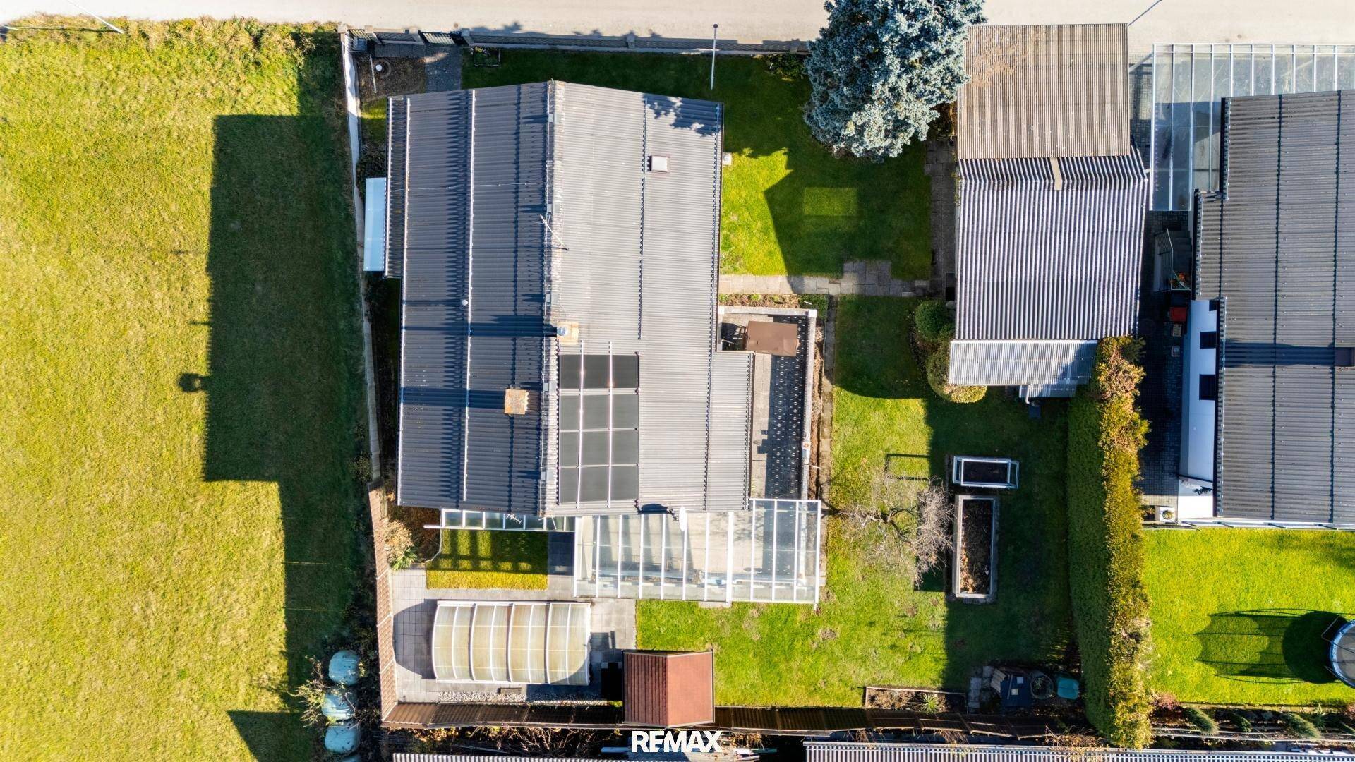 Vogelperspektive des Hauses mit Garten, Gewächshaus und Photovoltaikanlage auf dem Dach.