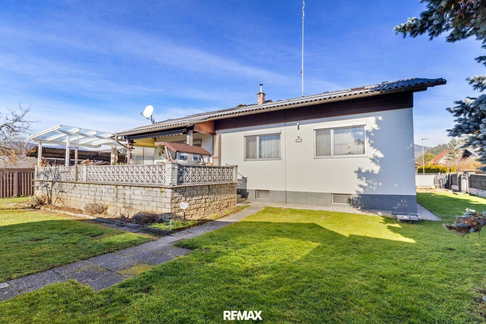 Seitenansicht des Hauses mit gepflegtem Rasen und einer erhöhten Terrasse mit dekorativem Geländer.