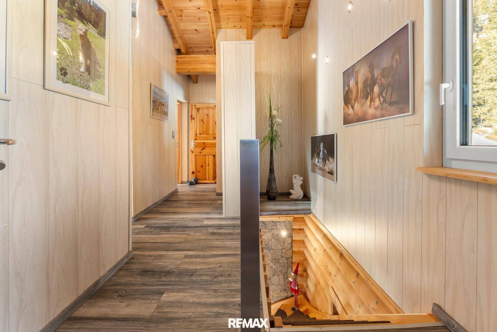 Heller Flur im Obergeschoss mit Holzverkleidung, Holzboden und Treppenabgang.