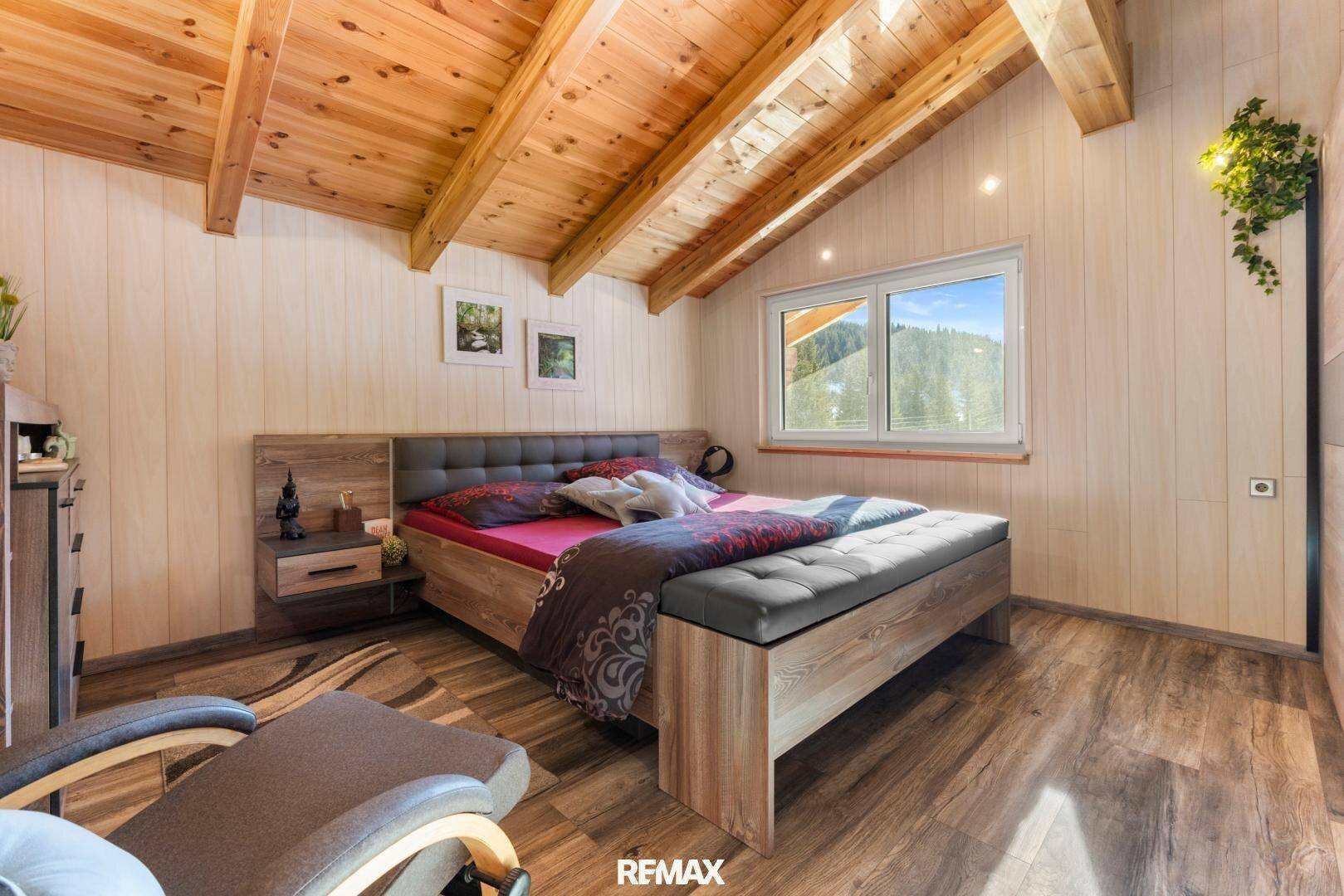 Helles Schlafzimmer mit Holzdachschräge, Holzboden und modernem Bett in ruhiger Lage.
