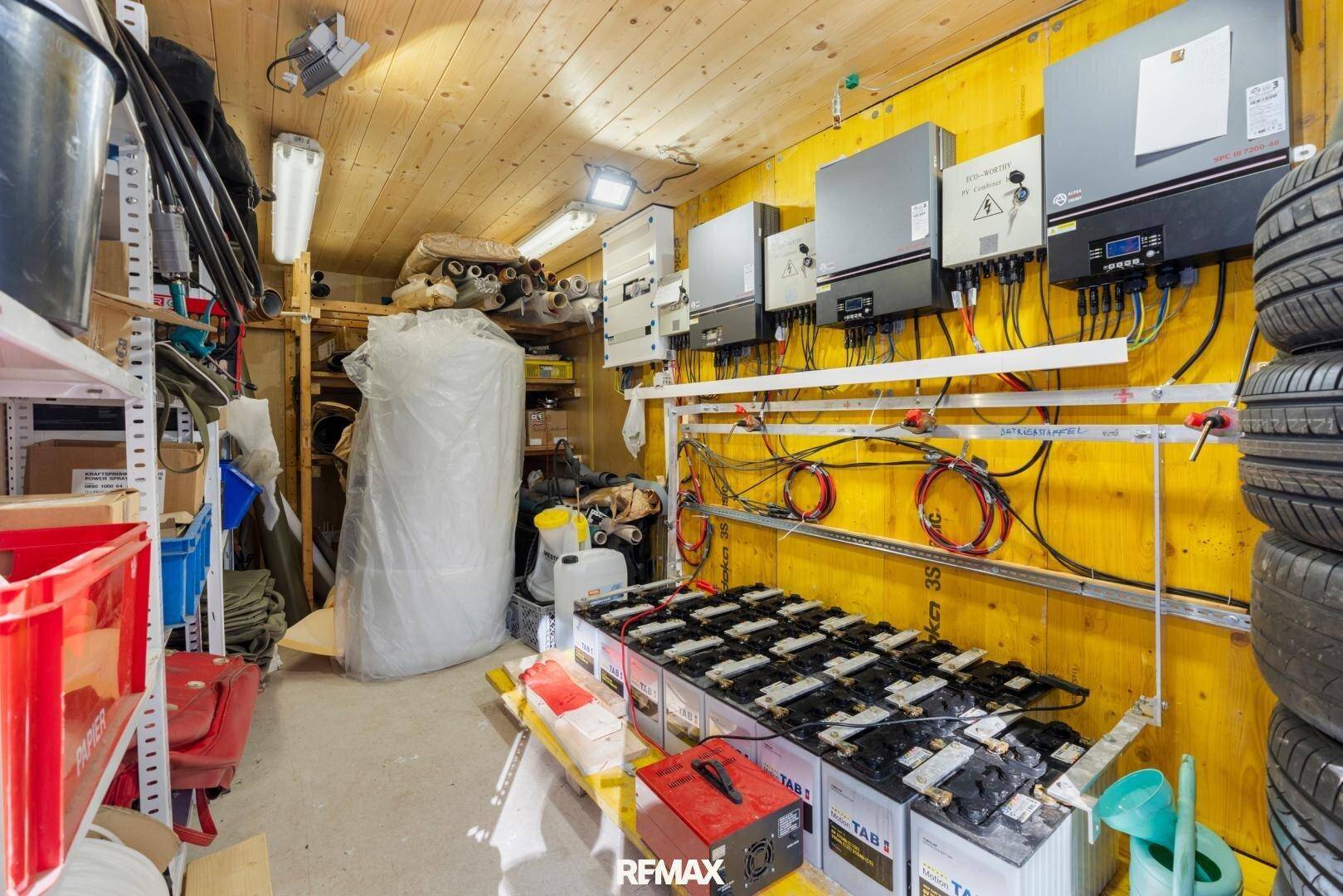 Technikraum mit Solaranlagen-Wechselrichtern, Batterien und Reifenlagerung.