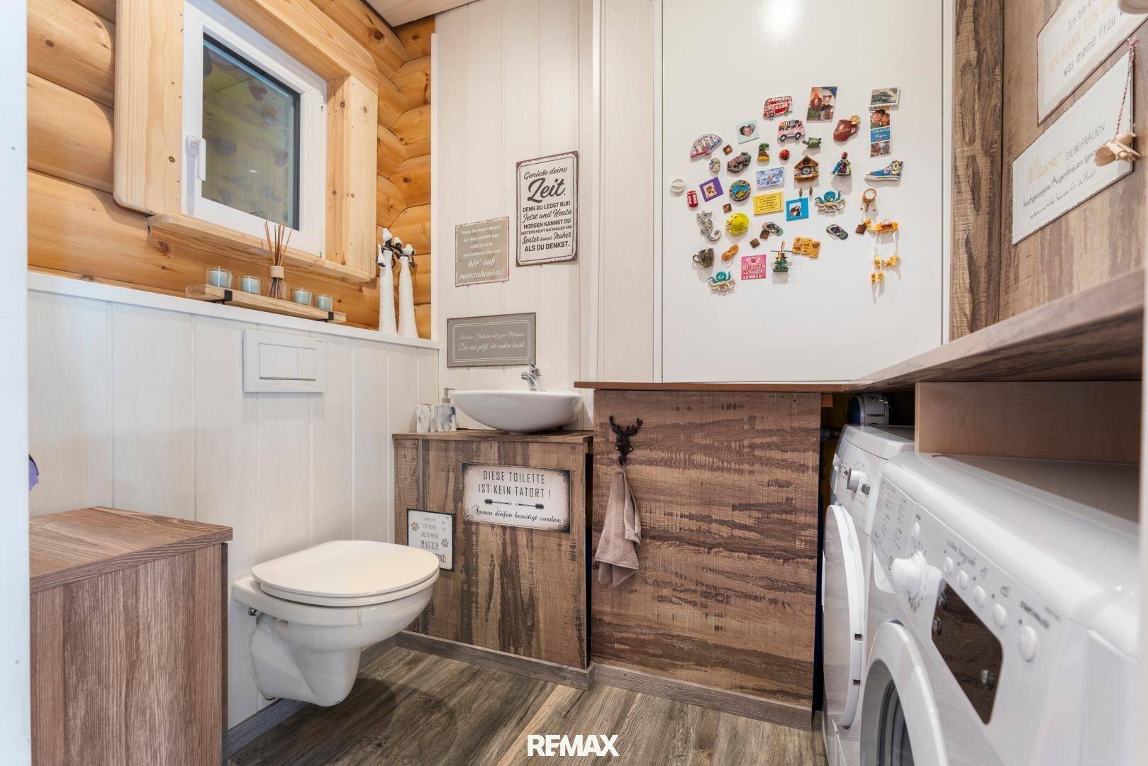 Praktisches Gäste-WC mit Waschbecken, Toilette und integrierter Waschmaschine in Holzoptik.