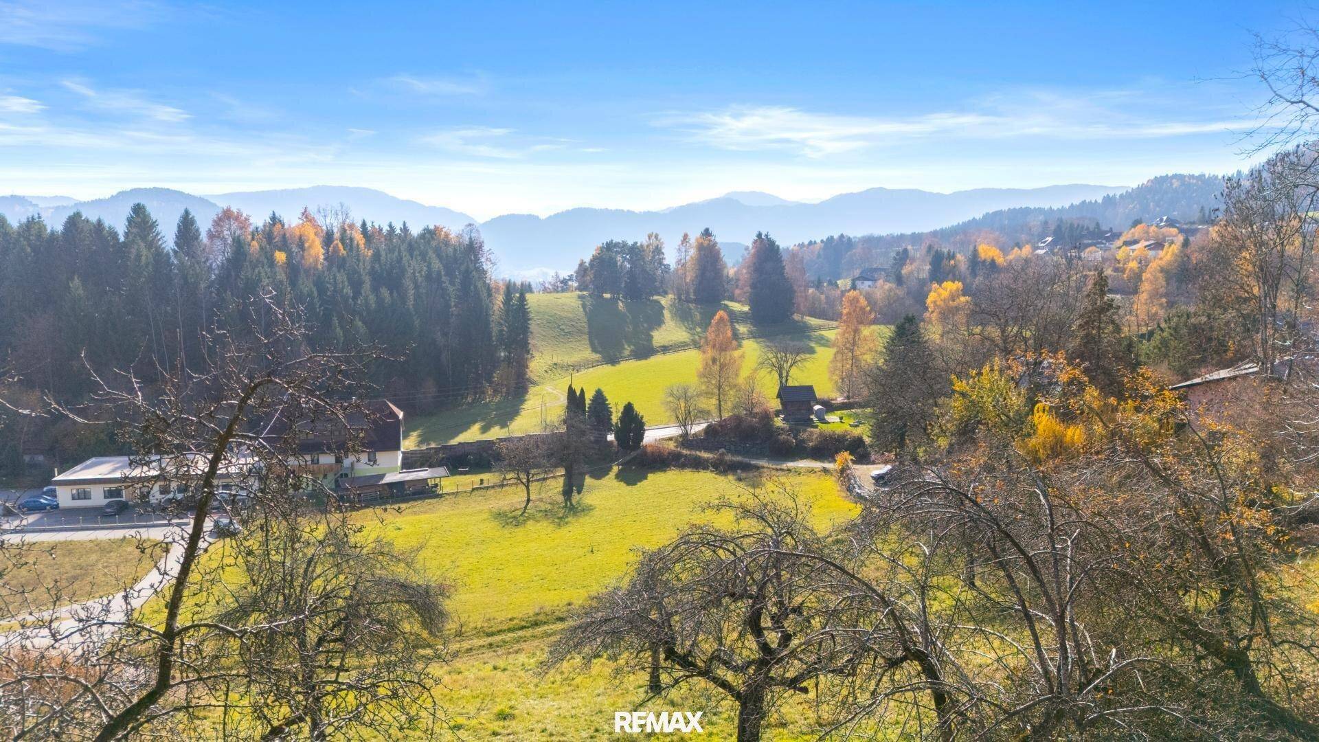 Weitläufiger Panoramablick über ein grünes Tal mit verstreuten Häusern und bewaldeten Hügeln.