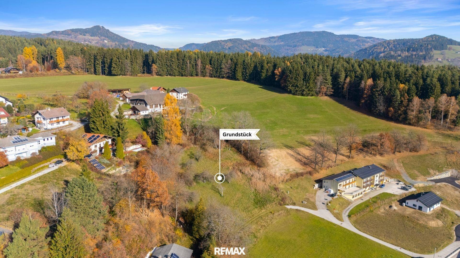 Weitläufige Landschaftsaufnahme eines Grundstücks mit umliegenden Häusern und Bergen im Hintergrund.