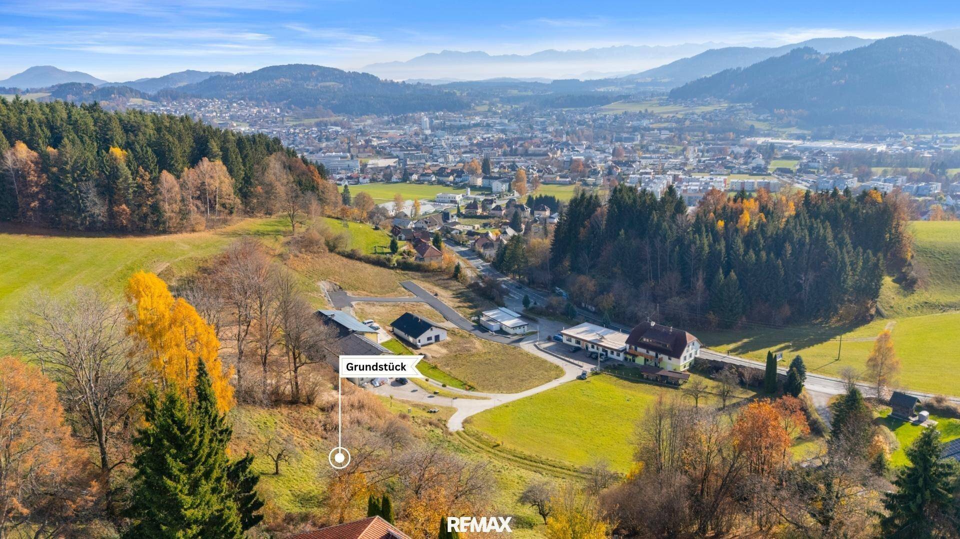 Panoramablick auf ein Grundstück mit angrenzender Stadt und weiten Bergketten am Horizont.