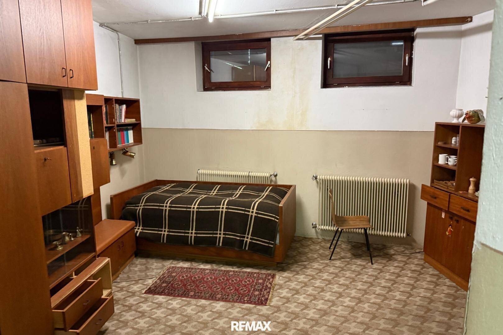 Kellerraum mit Bett, Schränken und Fenstern, der als zusätzlicher Wohnraum genutzt werden kann.