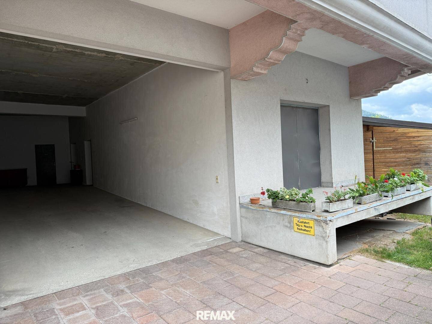 Offene Garageneinfahrt mit einem Aufzug daneben, der den Zugang zu den oberen Etagen ermöglicht.