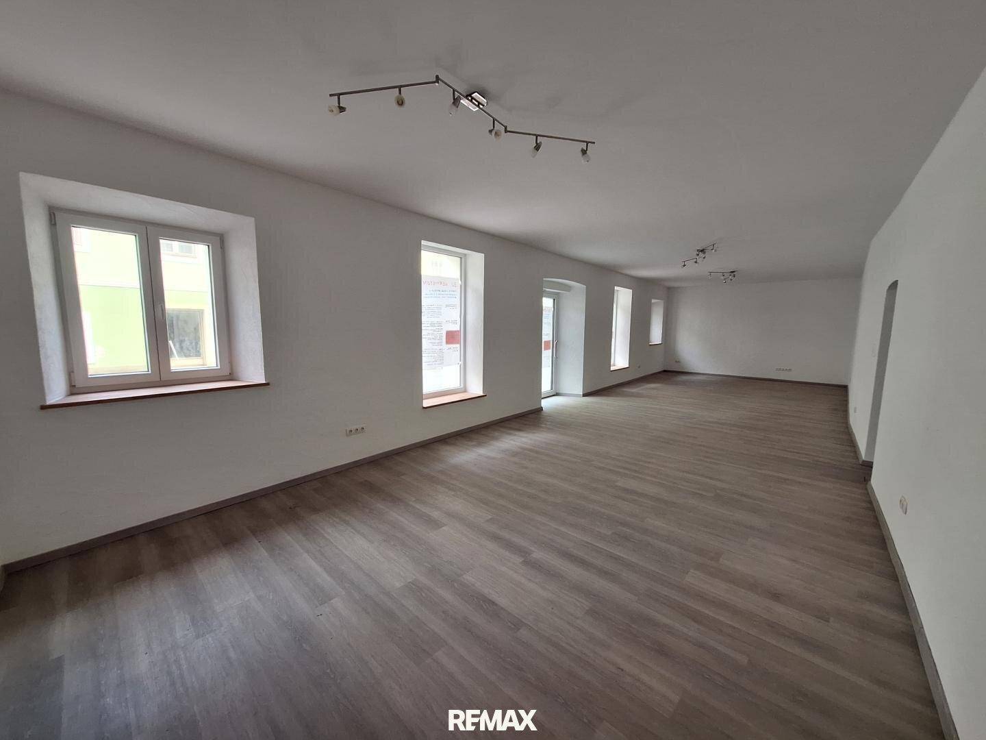 Langer, heller Raum mit Holzboden und mehreren Fenstern, geeignet für verschiedene Geschäftskonzepte.