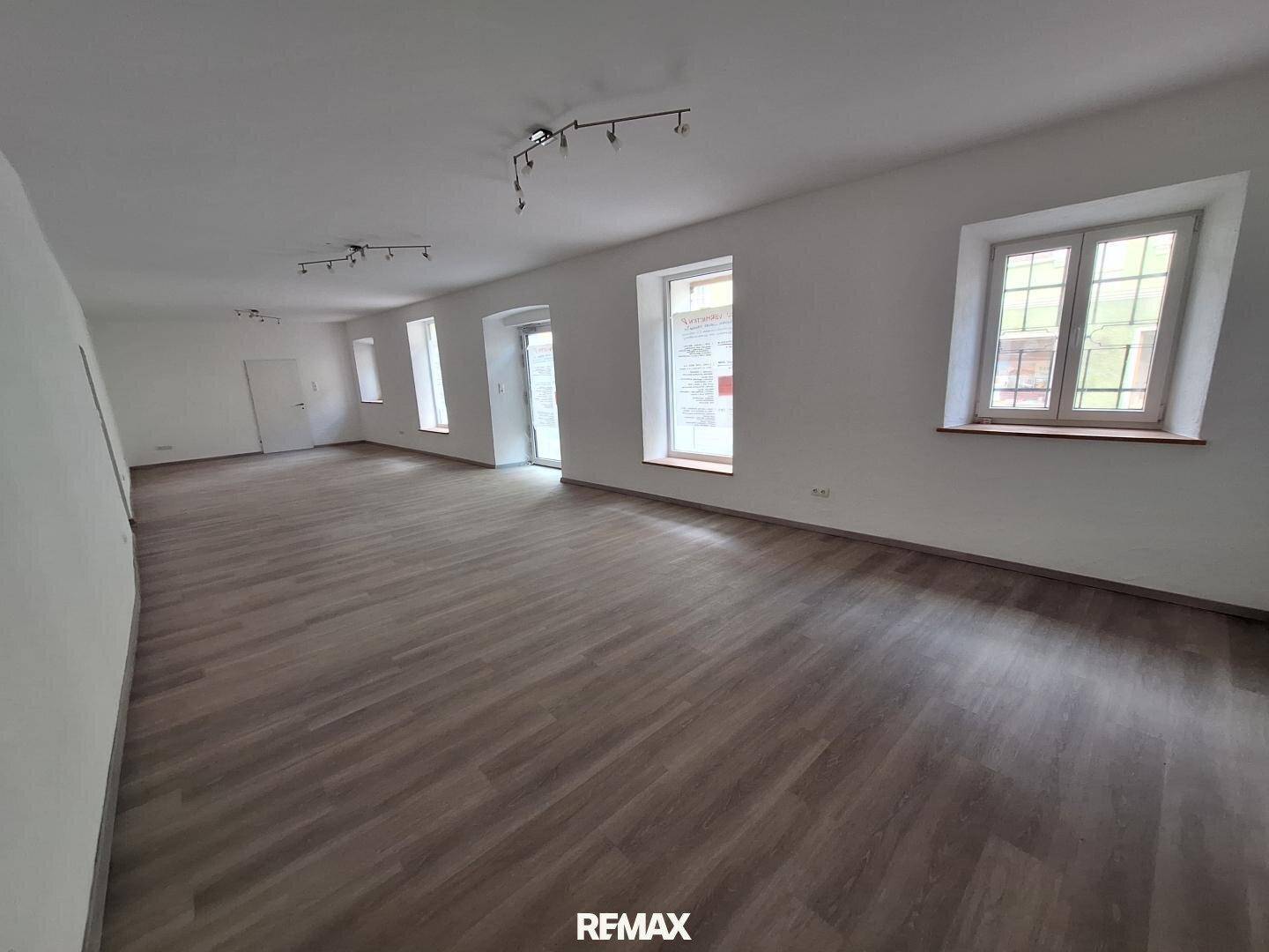 Großer, offener Raum mit Holzboden und vielen Fenstern, bietet viel Tageslicht.