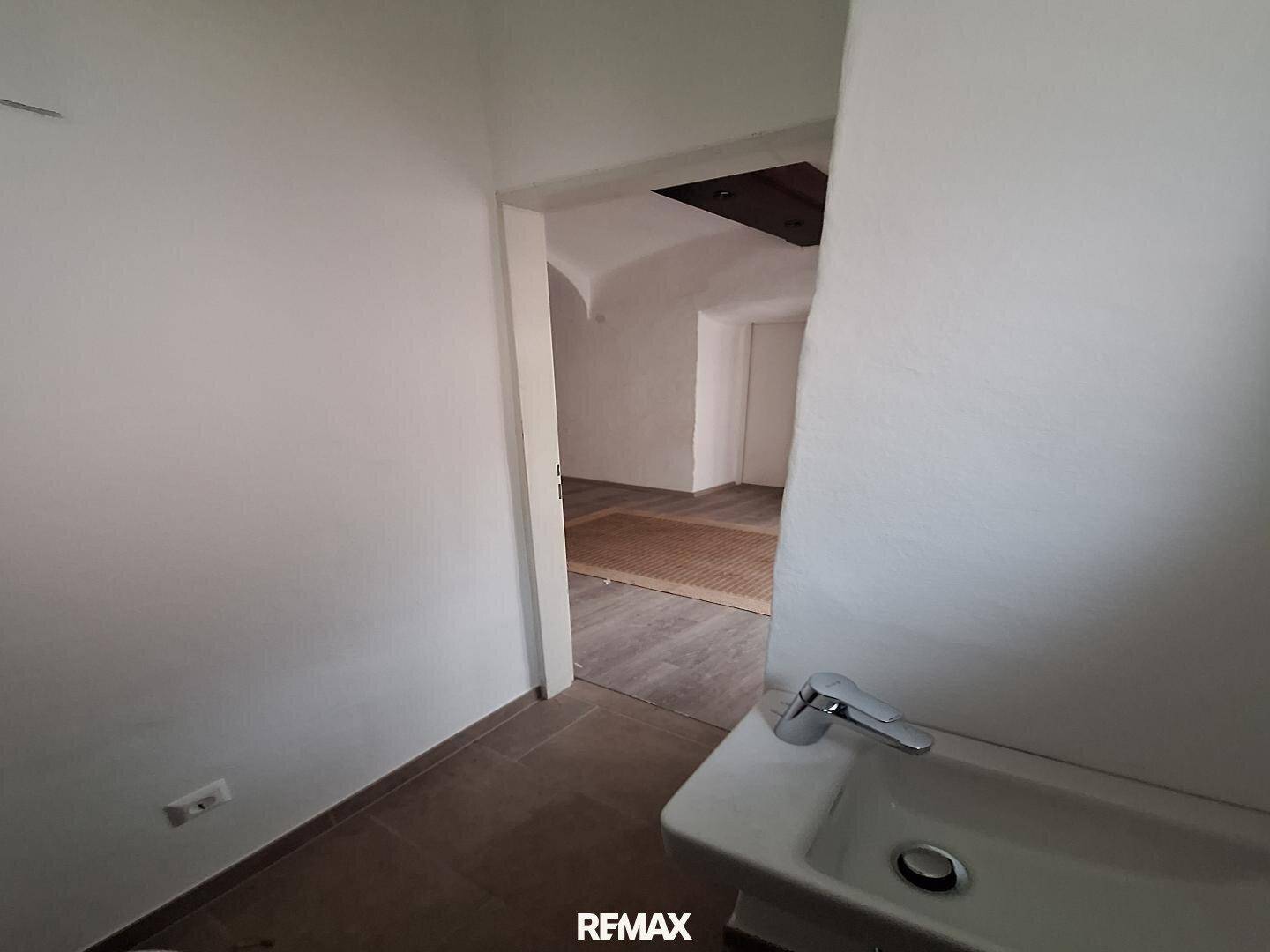 Eingangsbereich zum Gäste-WC mit Waschbecken, Blick in den angrenzenden Raum.