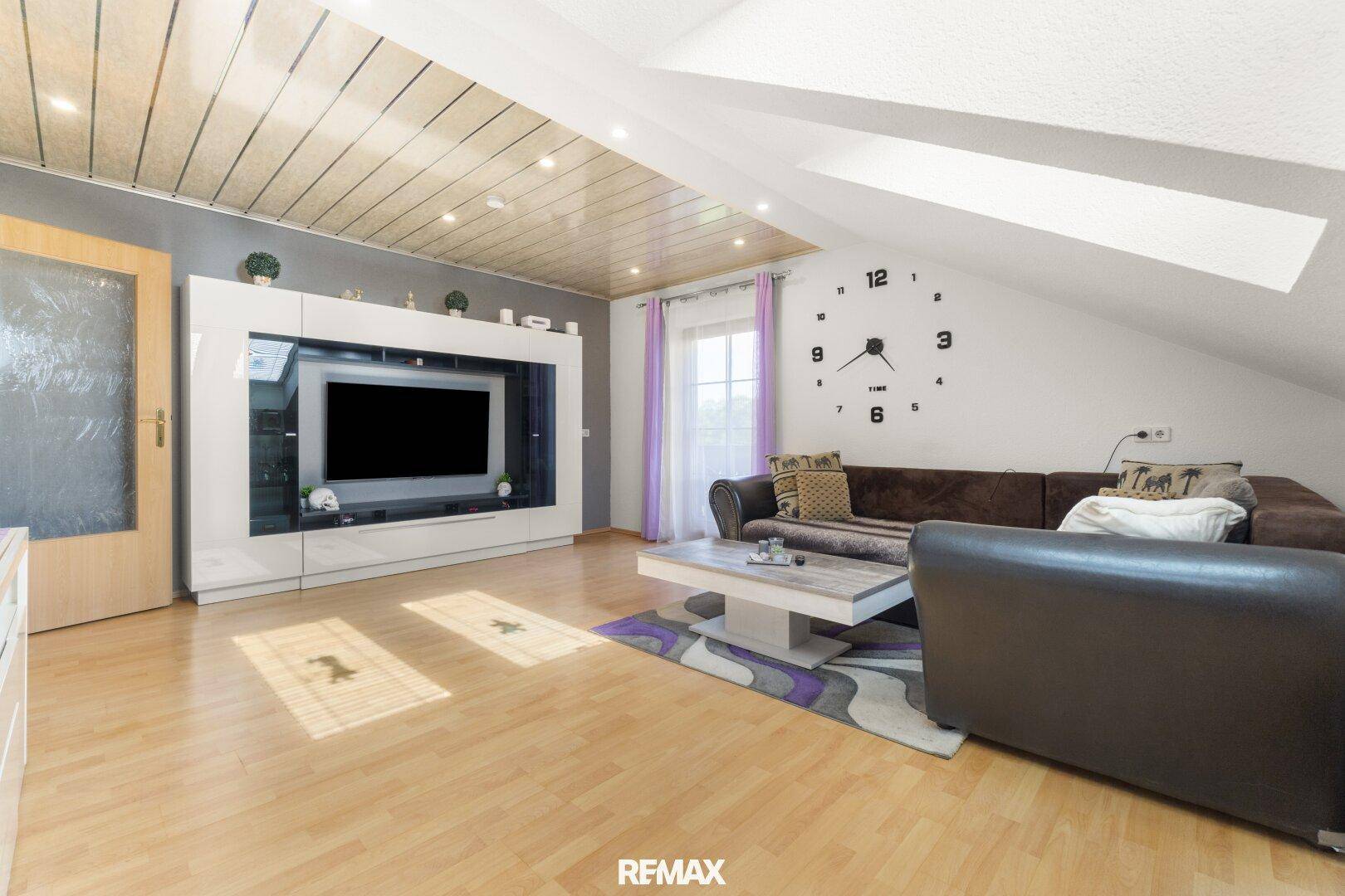 Geräumiges Wohnzimmer mit Dachschrägen, Holzboden und großem TV-Möbel.
