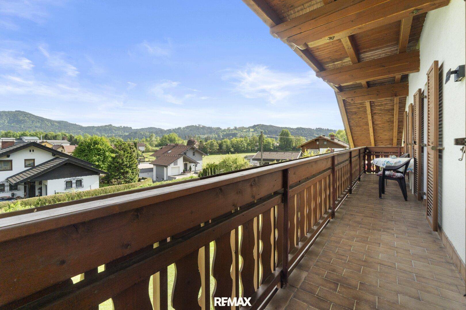 Langer Holzbalkon mit Fliesenboden und weitem Blick über die Landschaft.