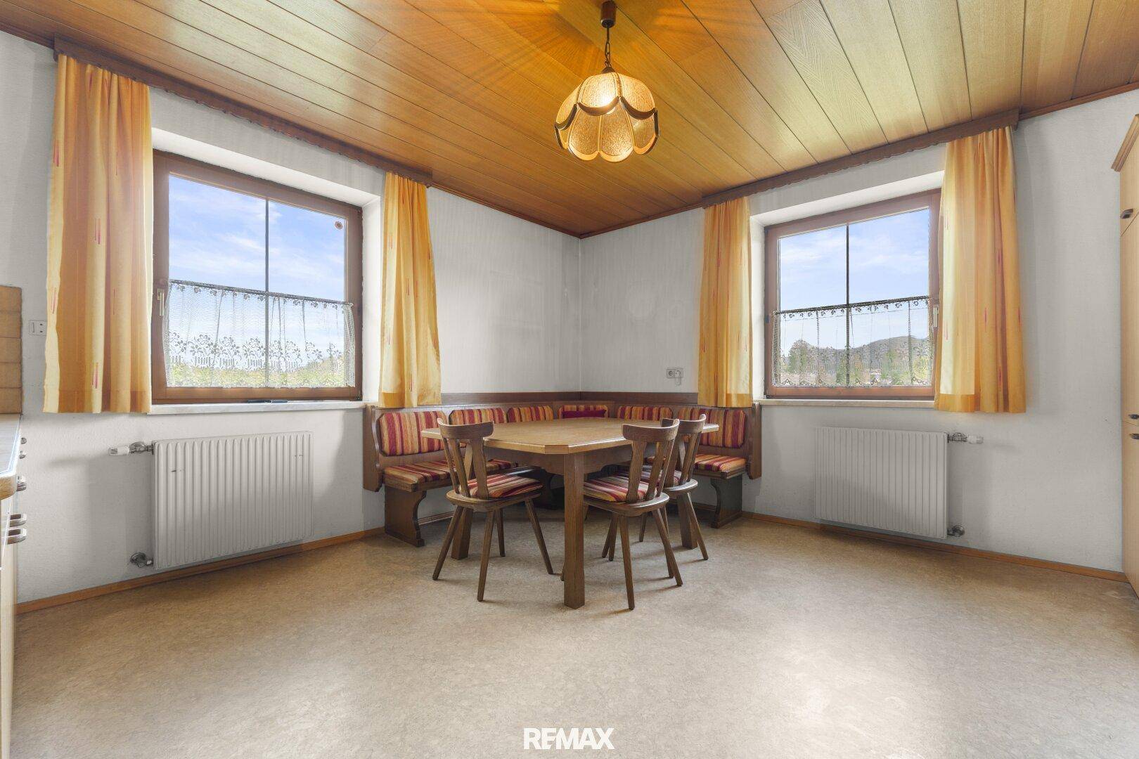 Gemütlicher Essbereich mit Eckbank, Holzdecke und zwei Fenstern.