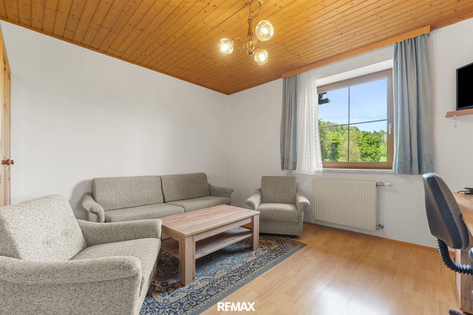 Helles Wohnzimmer mit bequemen Sofas, Holzboden und Blick ins Grüne.