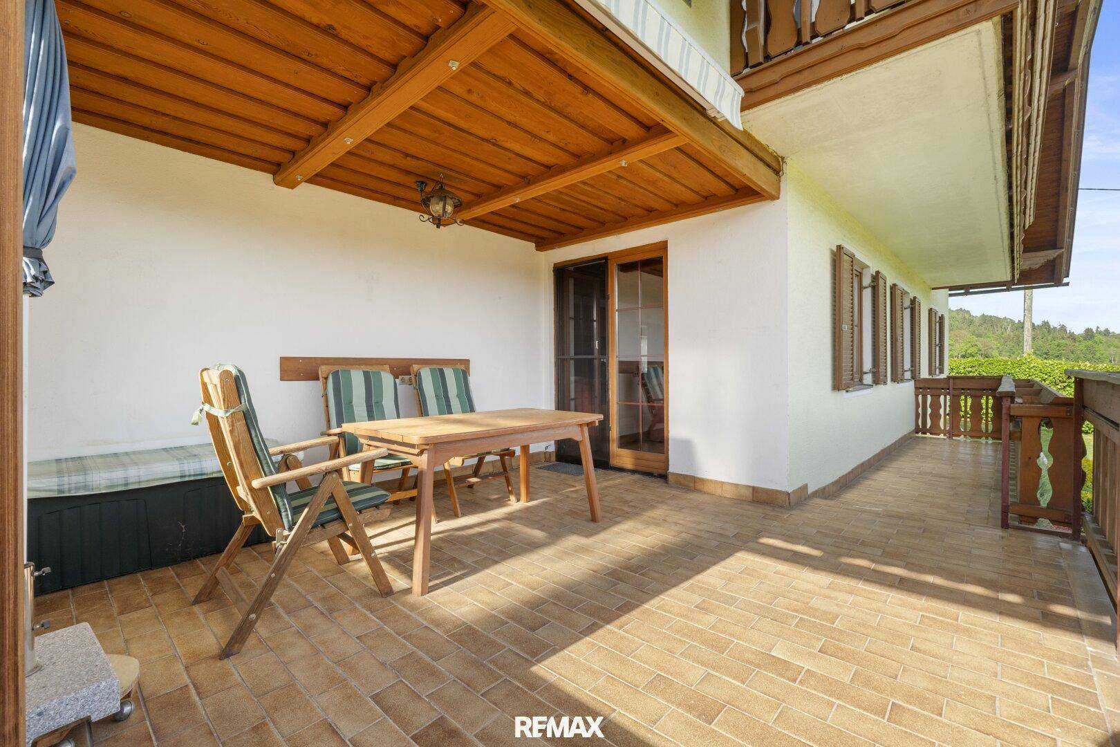 Überdachte Terrasse mit Fliesenboden und Gartenmöbeln für entspannte Stunden.