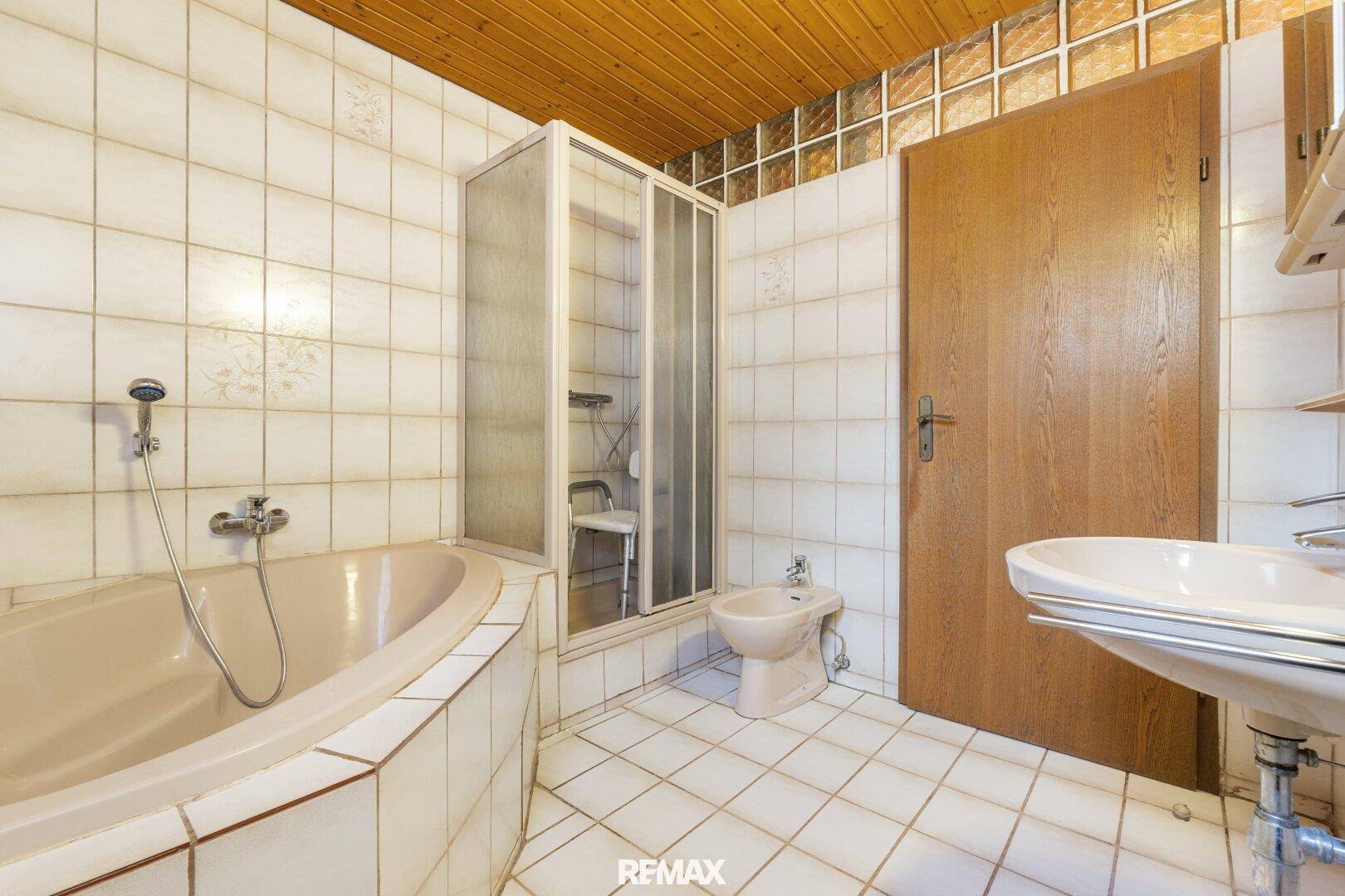 Gefliestes Badezimmer mit Badewanne, Dusche, Bidet und Einzelwaschbecken.