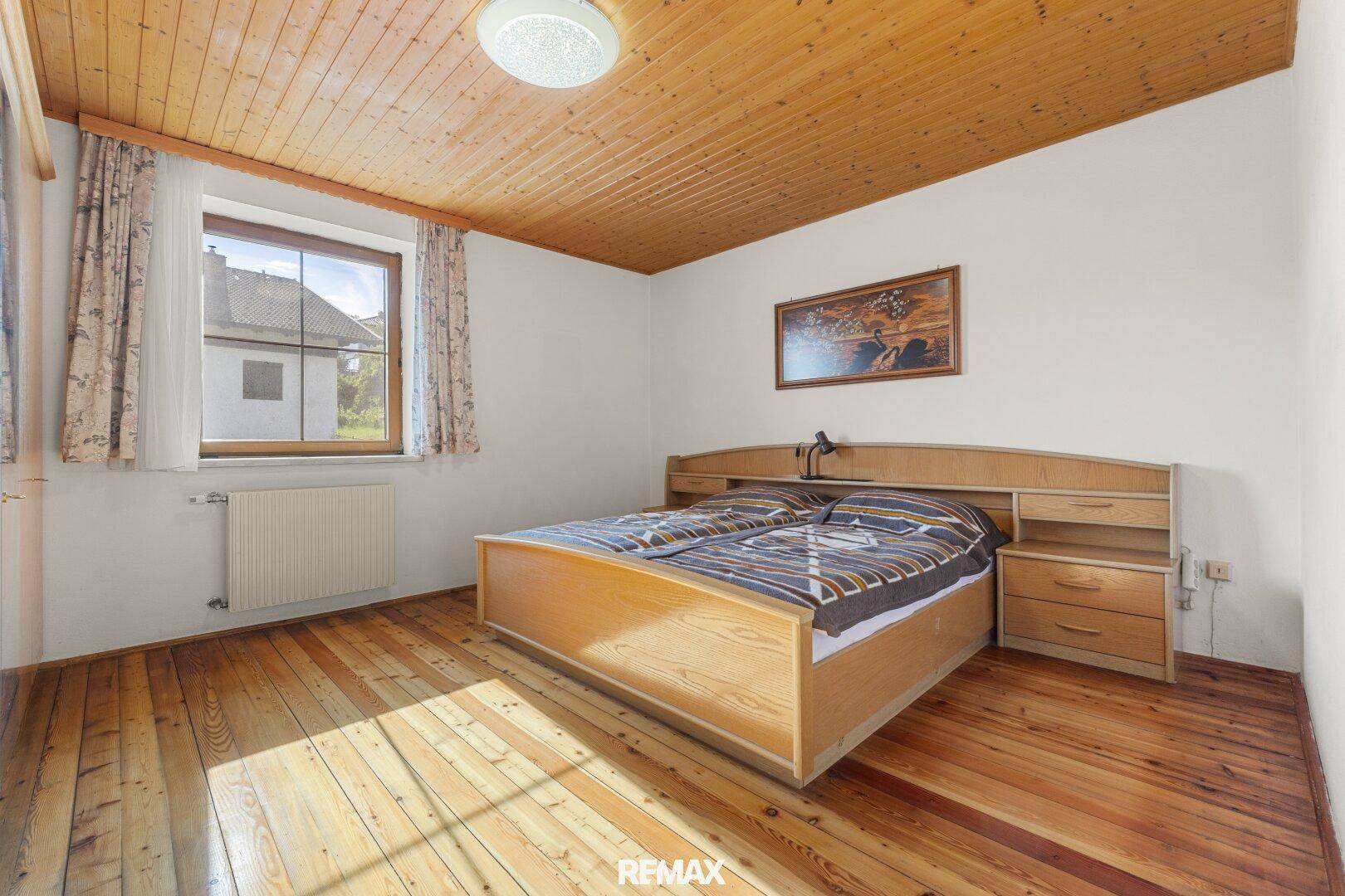 Schlafzimmer mit Holzboden, Holzdecke und traditionellem Bettgestell.
