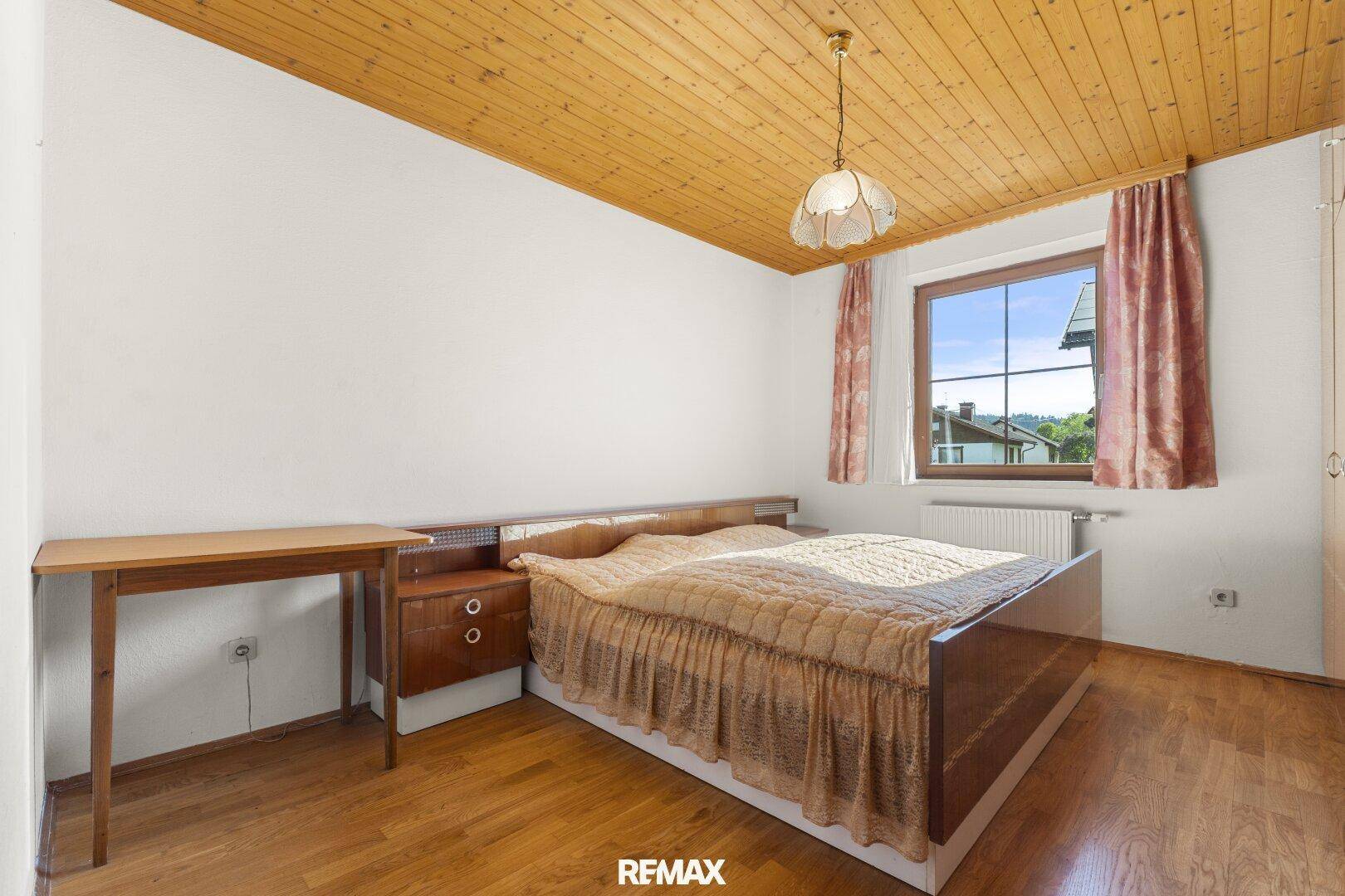 Helles Schlafzimmer mit Holzboden, Holzdecke und traditionellem Mobiliar.
