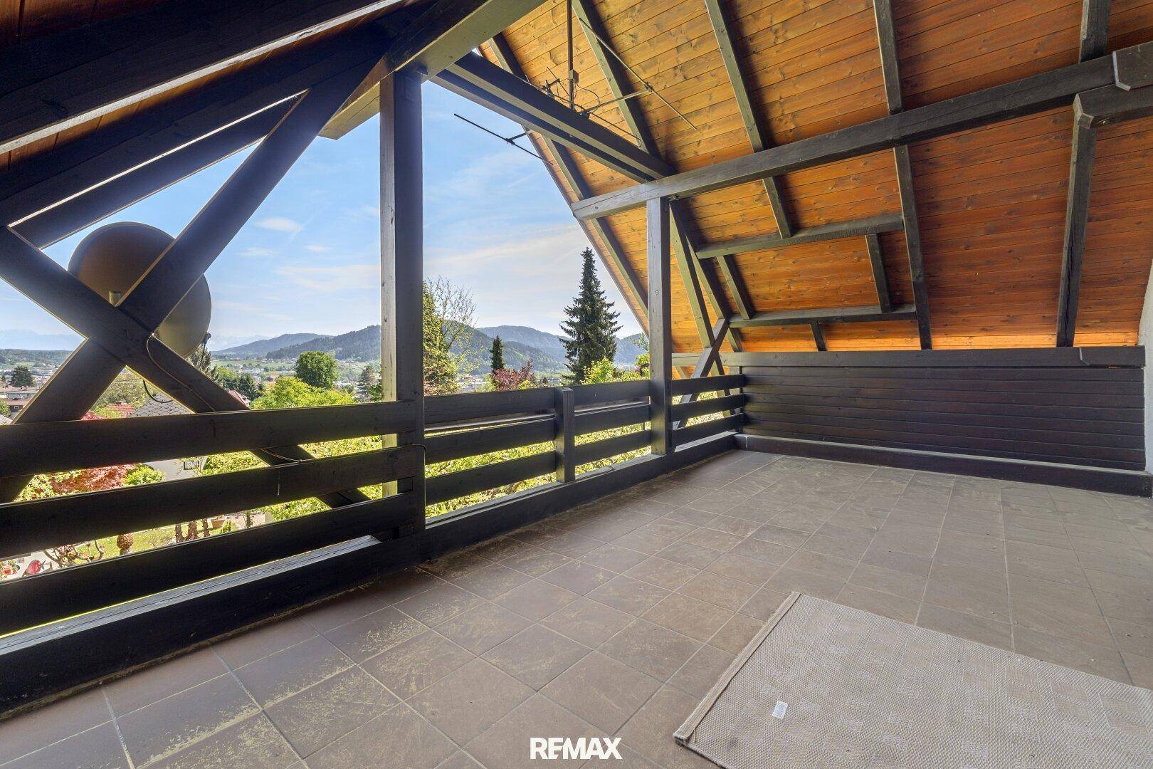 Großer überdachter Balkon mit Fliesenboden und weitem Blick auf die Landschaft.