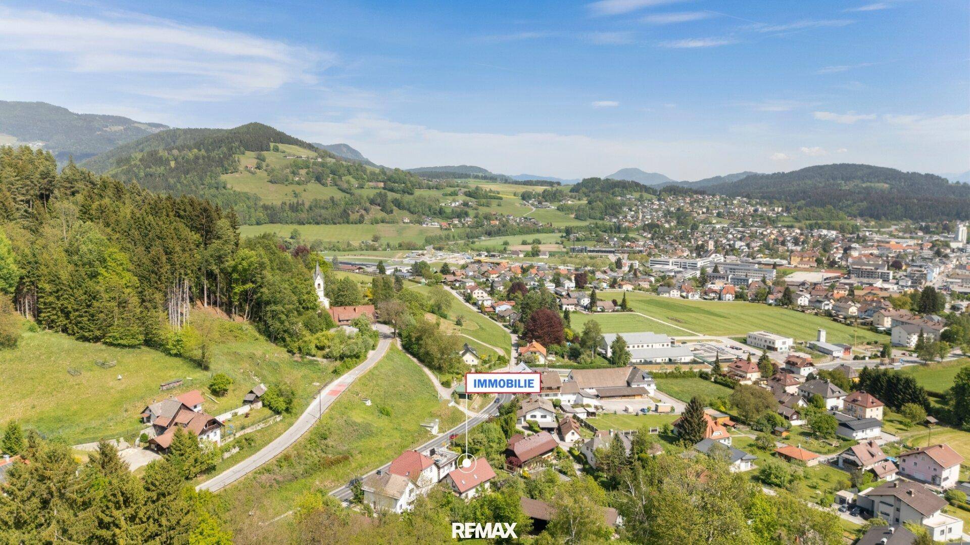 Luftaufnahme der Immobilie in einer grünen, ländlichen Umgebung mit Bergen im Hintergrund.