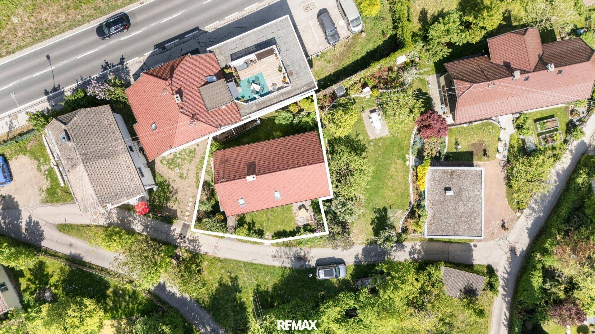 Vogelperspektive des Grundstücks mit Haus, Garten und angrenzender Straße.