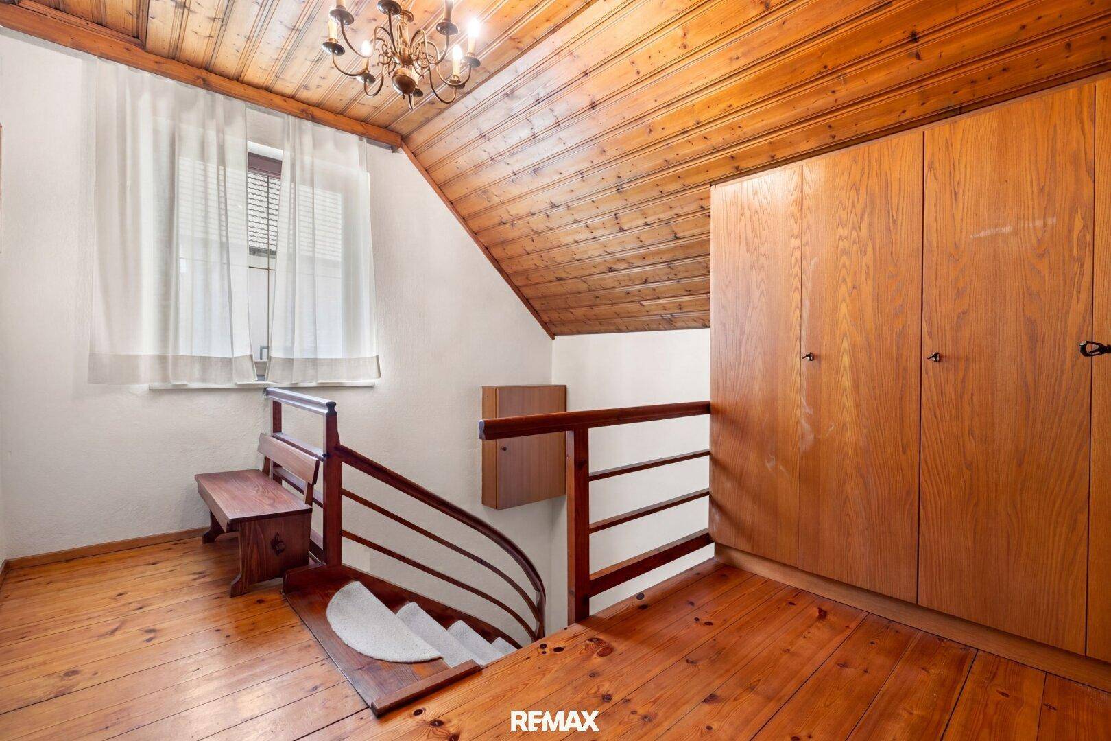 Oberer Flur mit Holzfußboden, Dachschräge und Einbauschränken aus Holz.