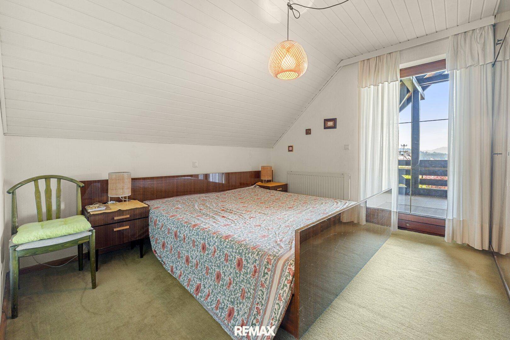 Schlafzimmer mit Teppichboden, Dachschräge und direktem Zugang zum Balkon.