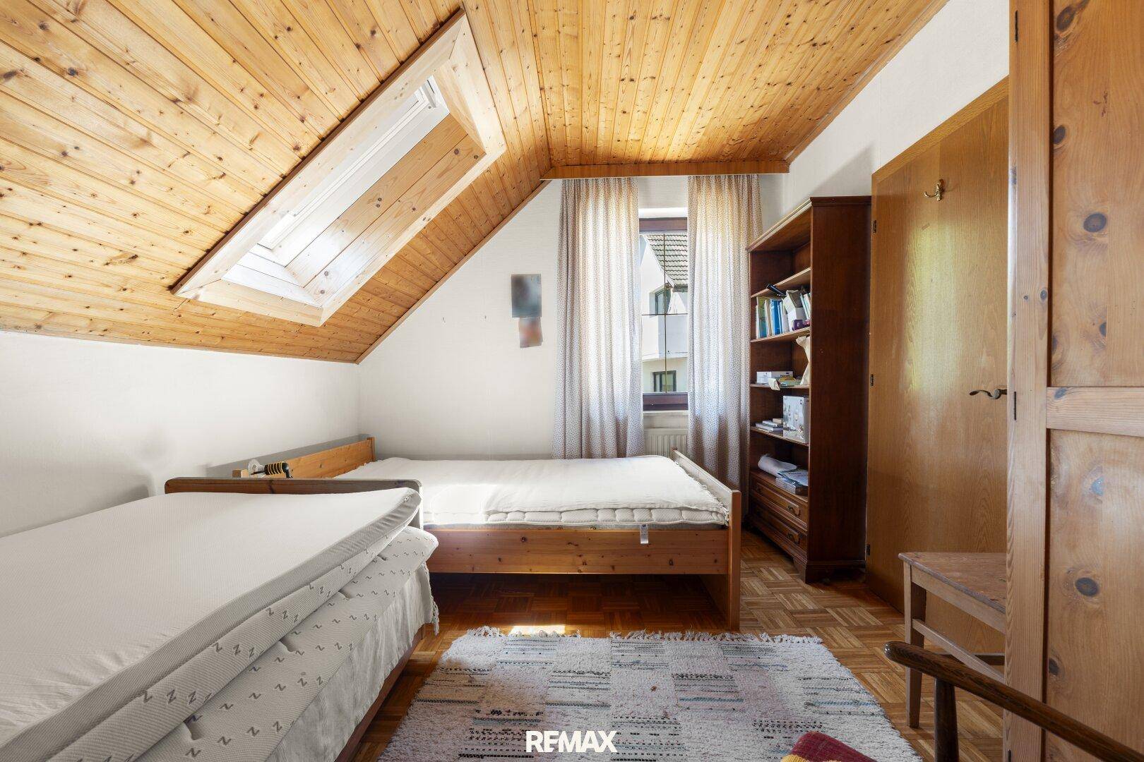 Geräumiges Schlafzimmer mit Parkettboden, Dachschräge und Holzdecke.