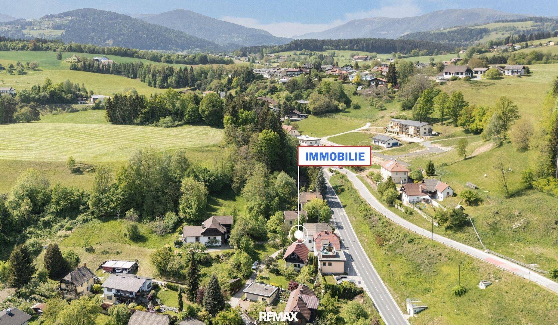 Weitläufige Luftaufnahme der Immobilie eingebettet in eine grüne Landschaft mit umliegenden Häusern.
