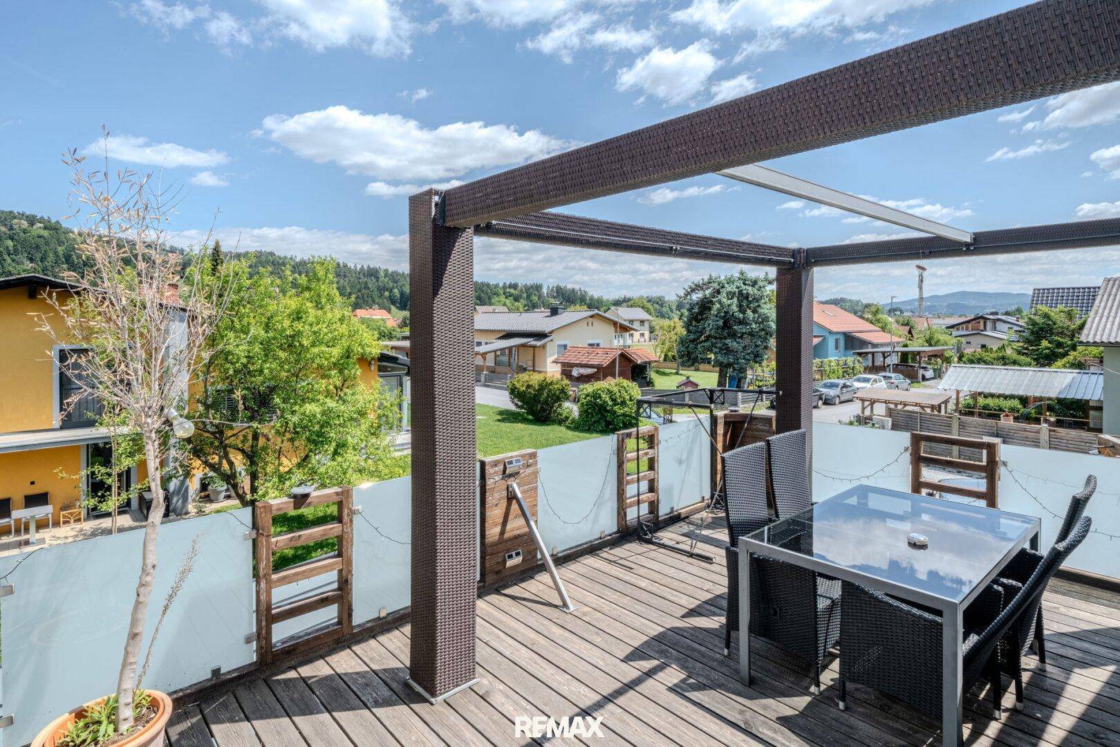 Möblierter Balkon mit Holzboden und Pergola, ideal für entspannte Stunden im Freien.