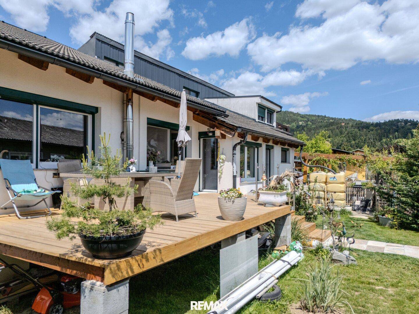 Große Holzterrasse mit Gartenmöbeln und Blick auf den Gartenbereich.
