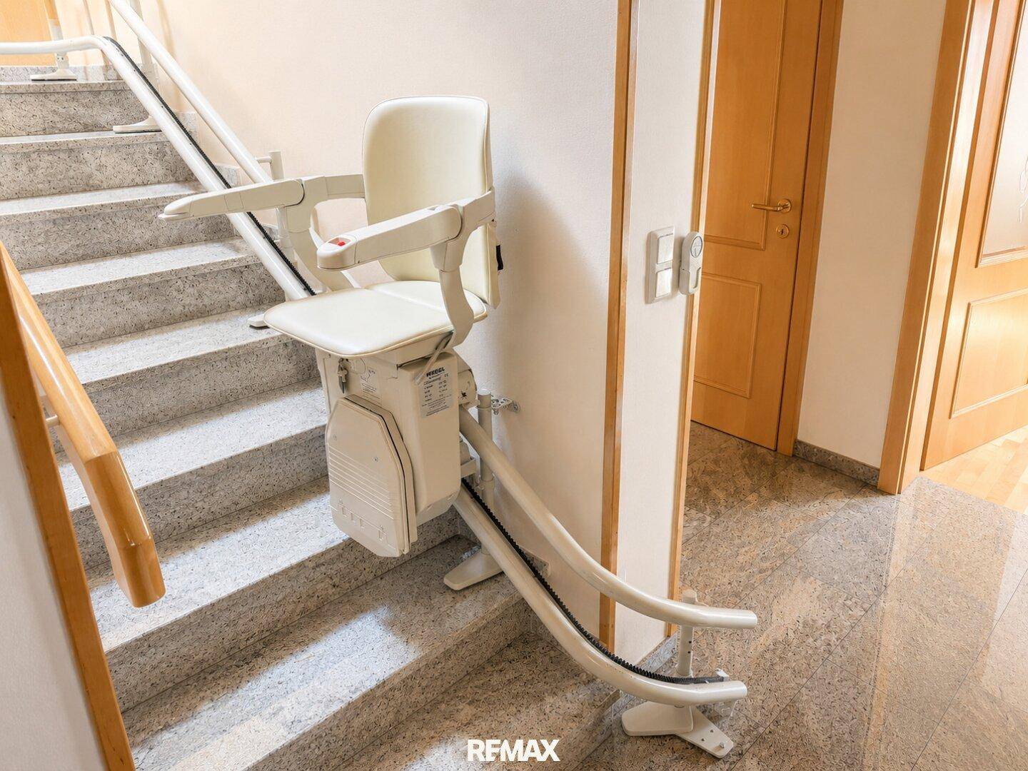 Treppenhaus mit Marmorstufen und installiertem Treppenlift für barrierefreien Zugang.