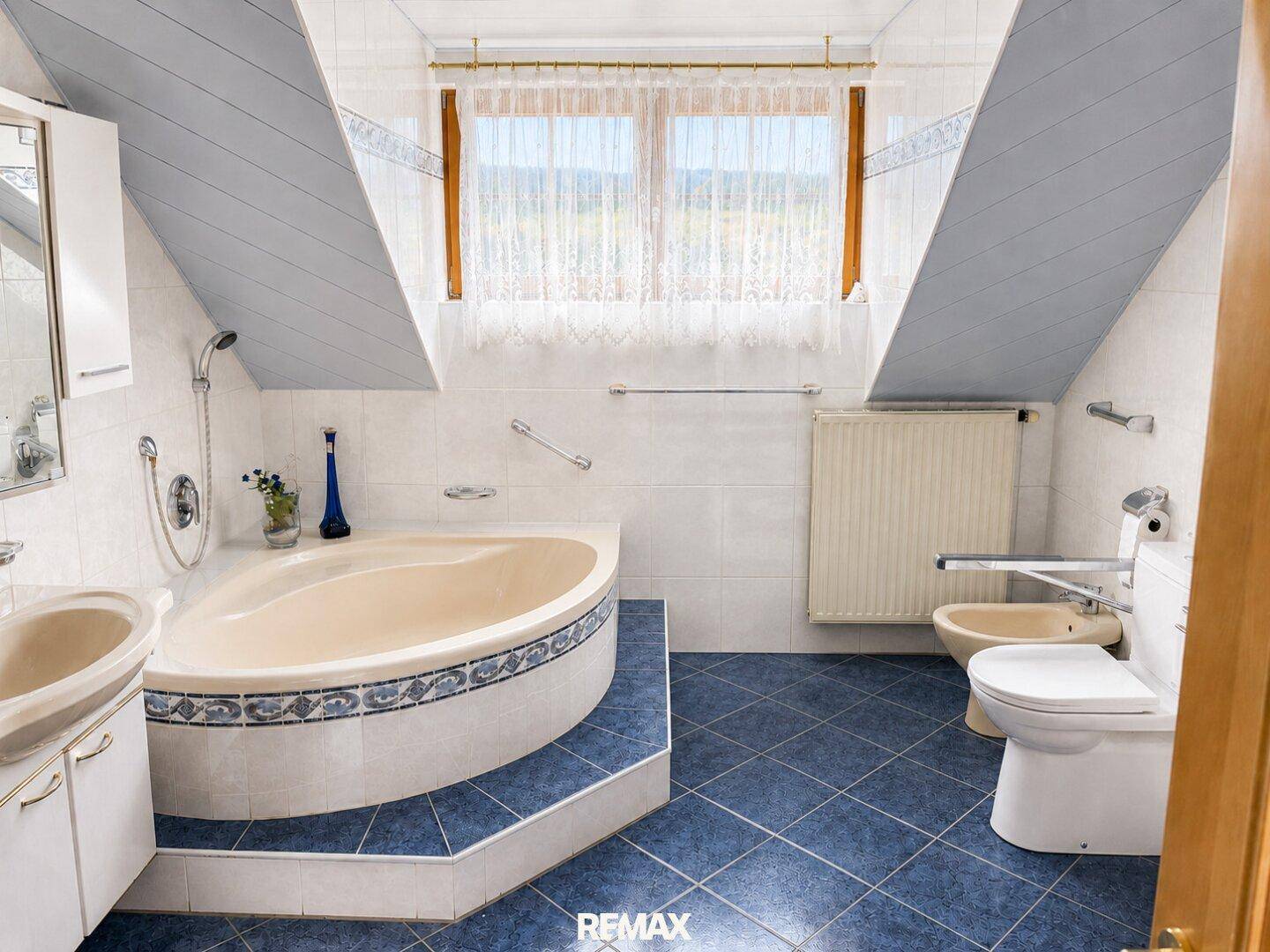 Geräumiges Badezimmer im Dachgeschoss mit Eckbadewanne, Bidet und Fenster.