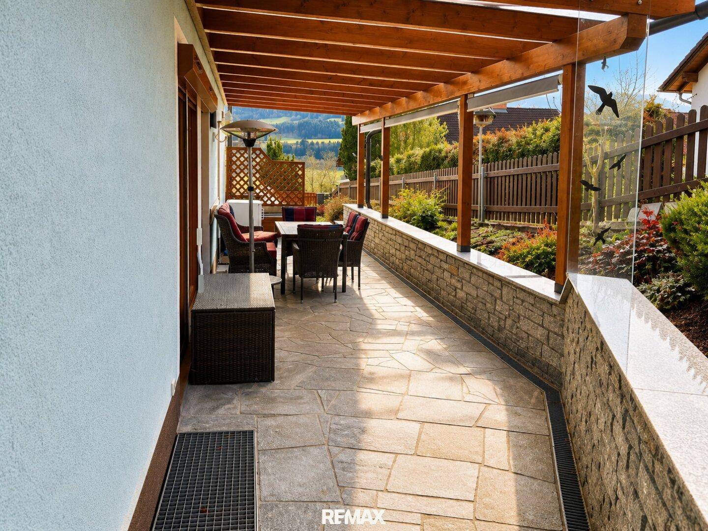 Überdachte Terrasse mit Sitzgelegenheiten und weitem Blick auf die Landschaft.