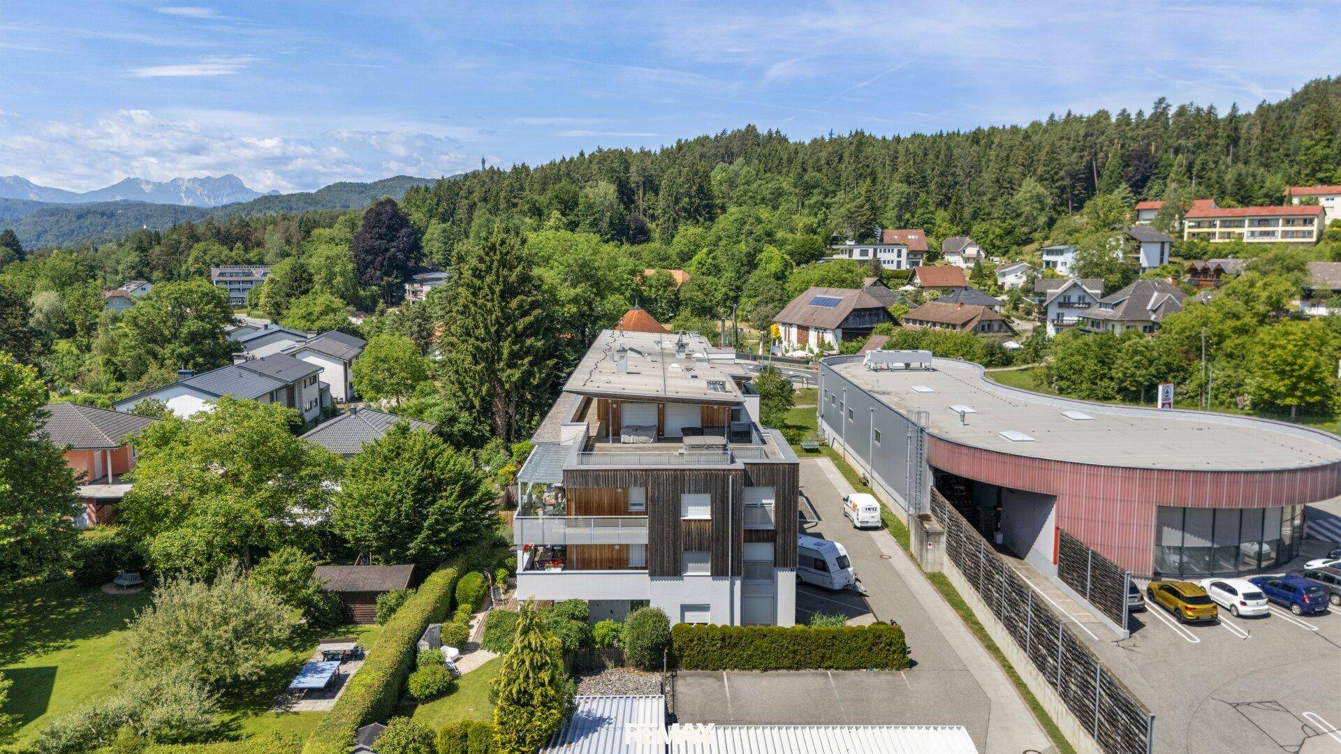 Luftaufnahme der modernen Wohnanlage in einer grünen Wohngegend mit Bergblick.