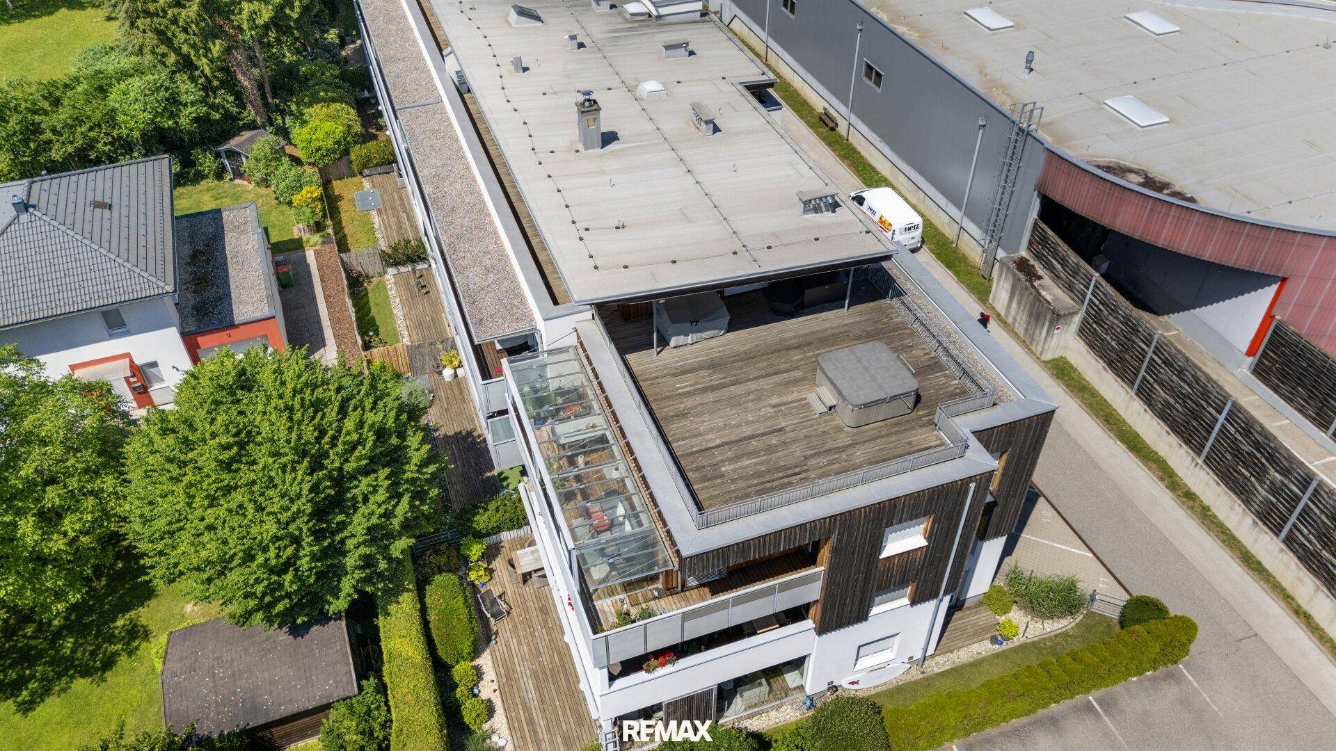 Dachterrassenbereich mit Holzbelag und Glasgeländer, umgeben von grüner Landschaft.