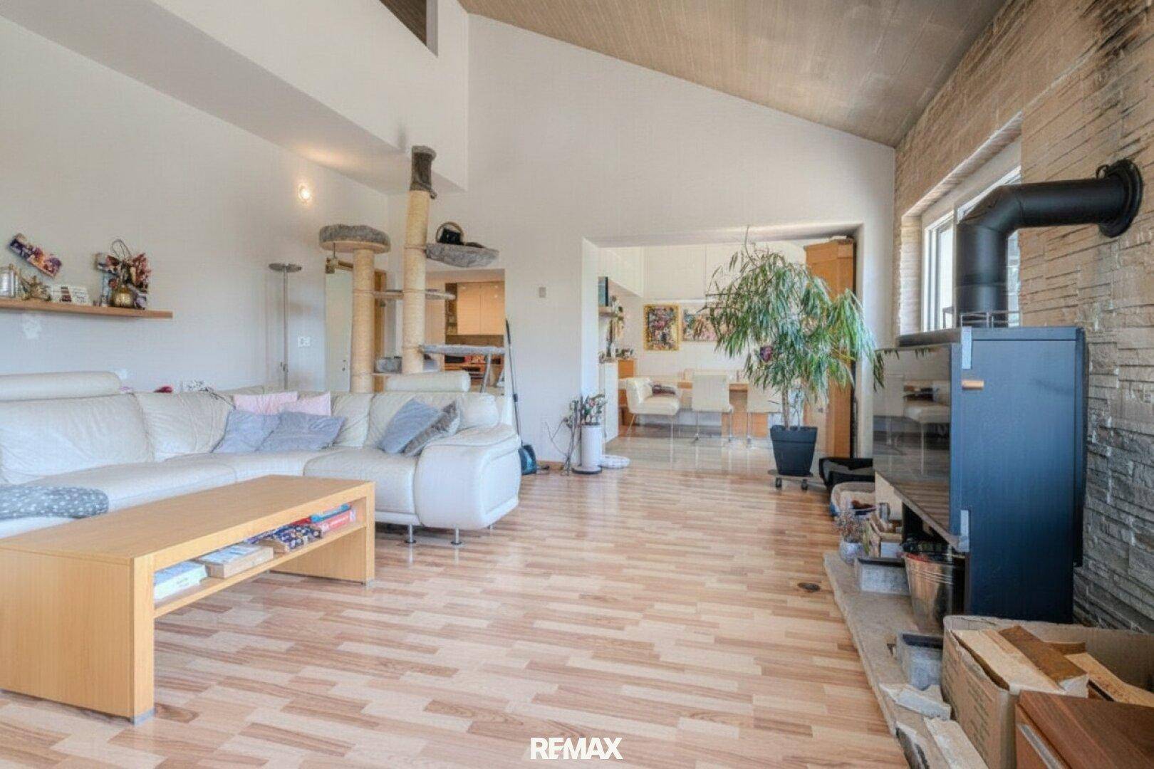 Geräumiges Wohnzimmer mit Holzboden, Kaminofen und gemütlicher Sitzecke.