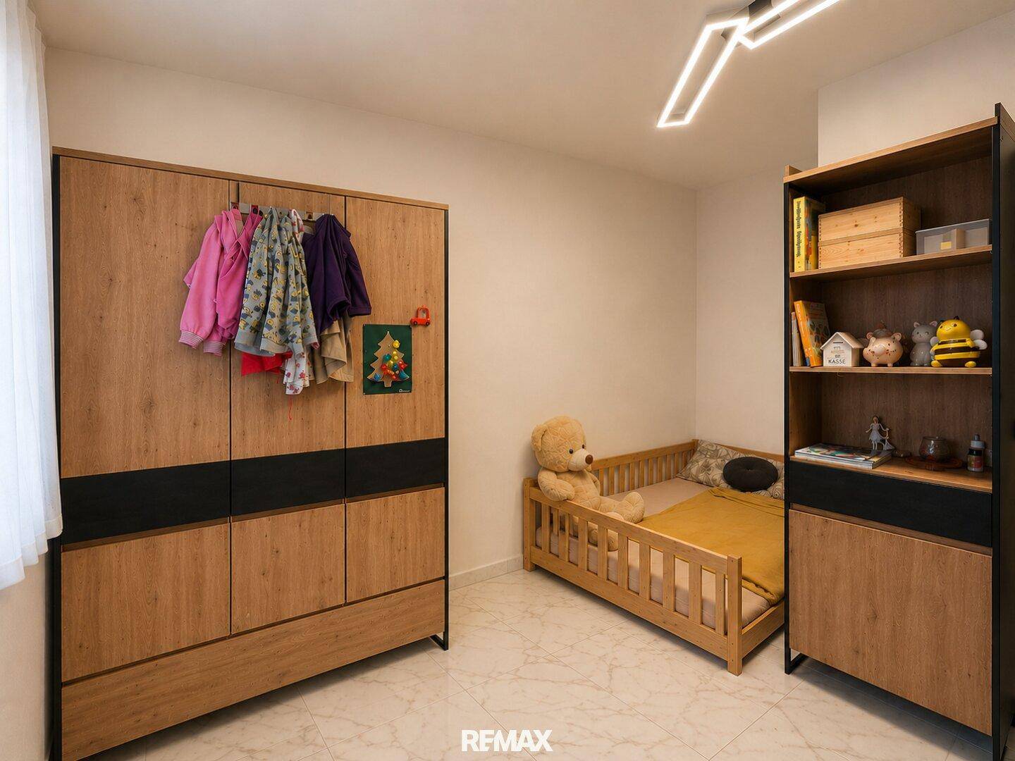 Freundliches Kinderzimmer mit kleinem Bett, Kleiderschrank und Bücherregal.