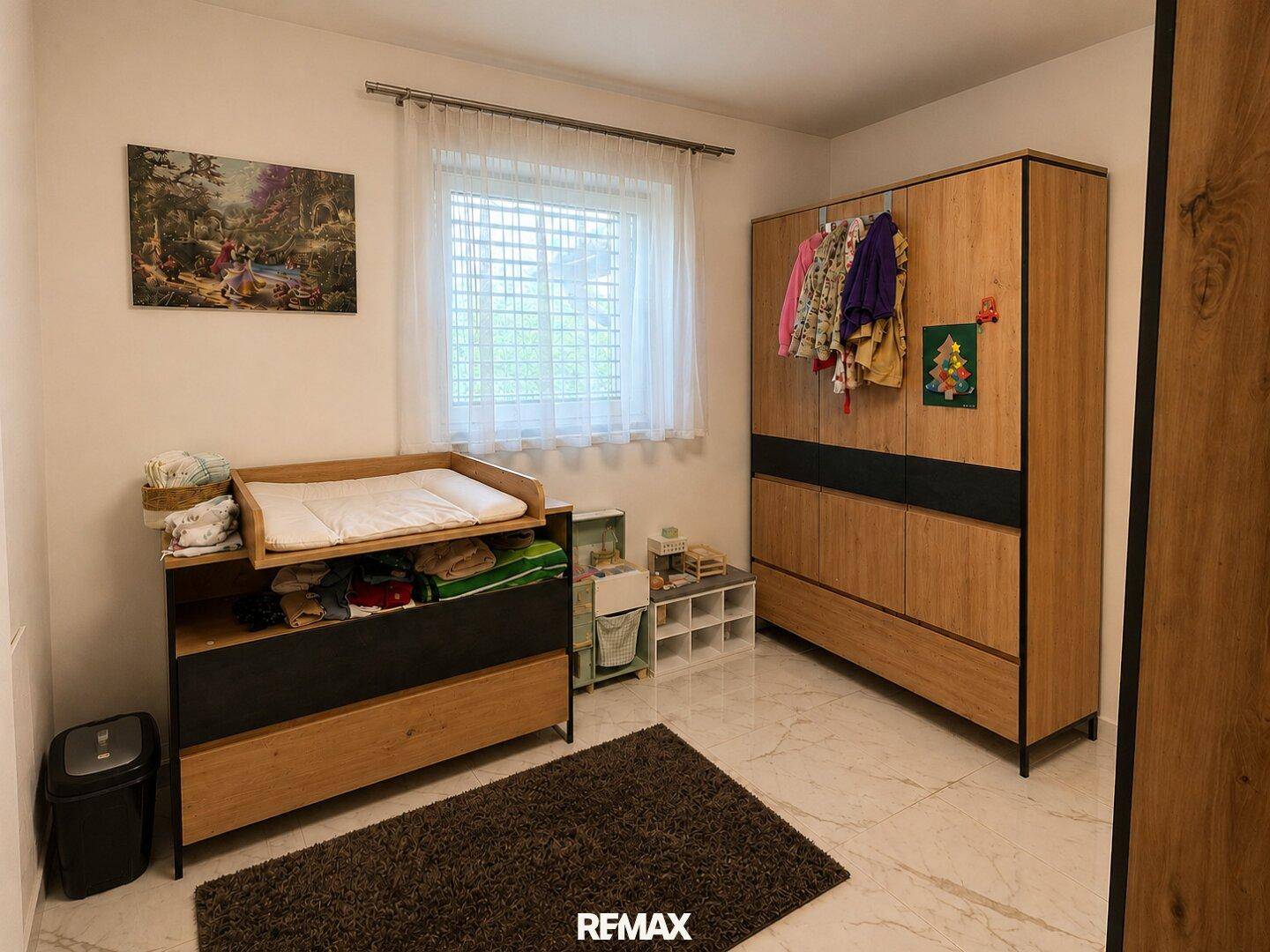Kinderzimmer mit Wickeltisch, großem Kleiderschrank und hellem Fliesenboden.