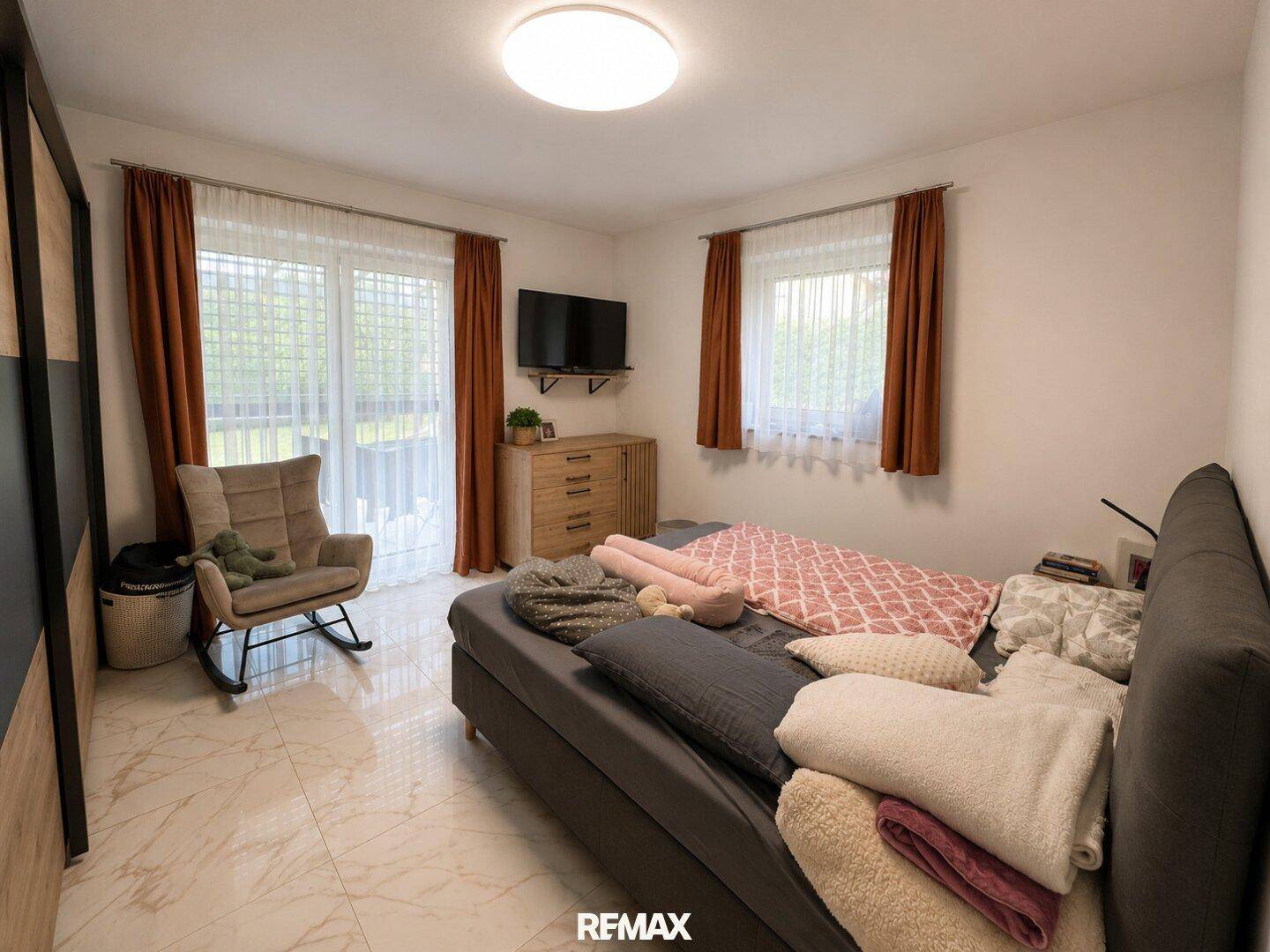 Helles Schlafzimmer mit Zugang zum Außenbereich, modernem Bett und Fliesenboden.