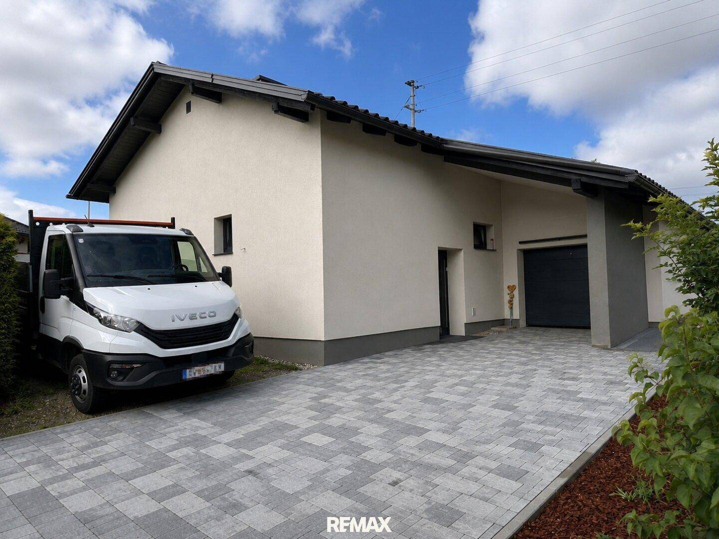 Vorderansicht des Hauses mit gepflasterter Zufahrt, Garage und gepflegtem Vorgarten.