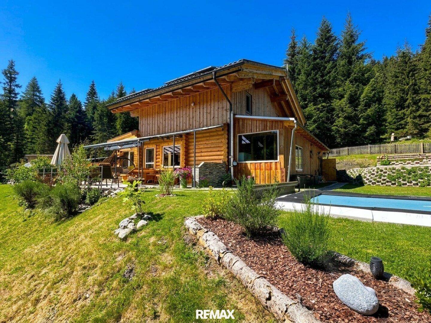 Rustikales Holzhaus mit weitläufigem Garten und einem erfrischenden Pool in alpiner Umgebung.
