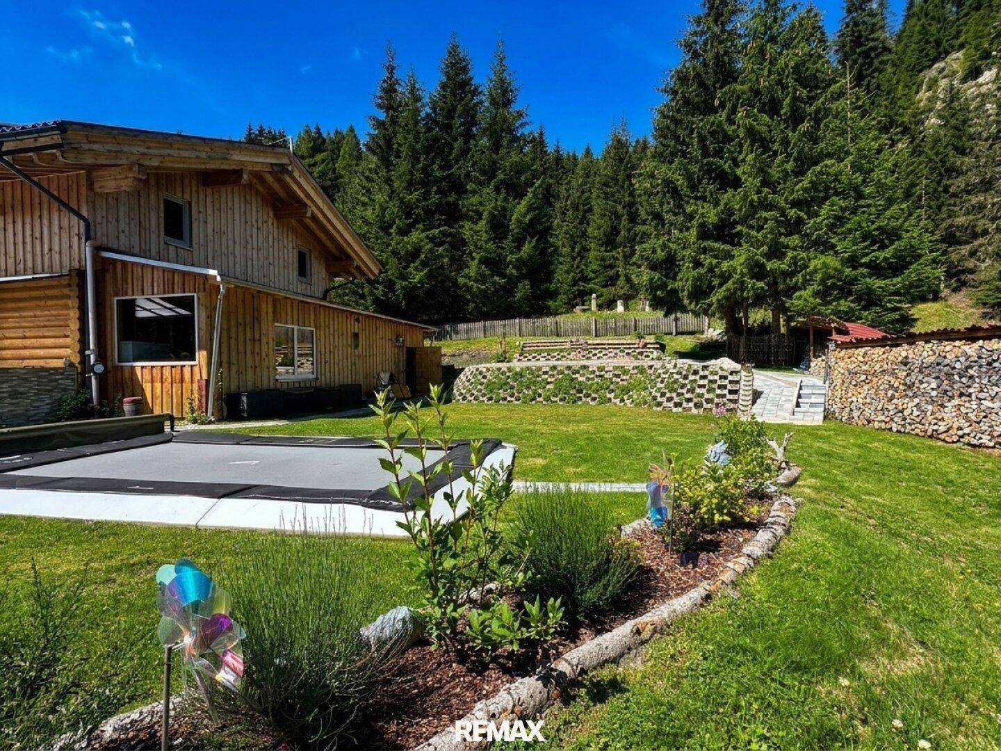 Blühender Garten mit Blumenbeeten, Sträuchern und dem charmanten Holzhaus.