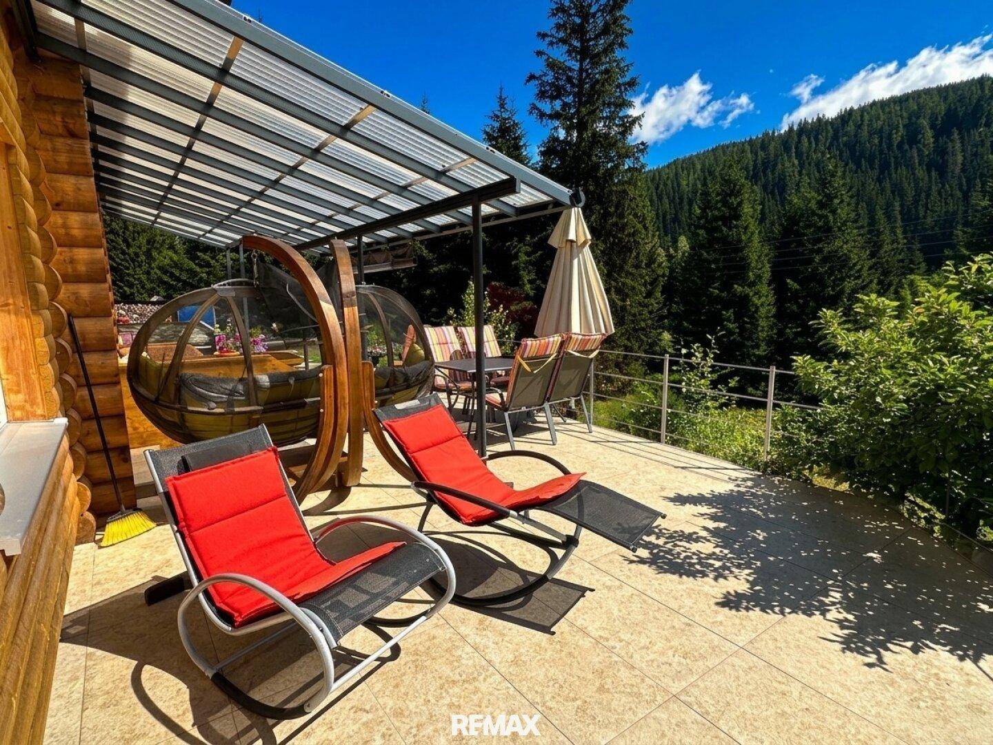 Überdachte Terrasse mit Liegestühlen und einer einzigartigen kugelförmigen Sitzgelegenheit.