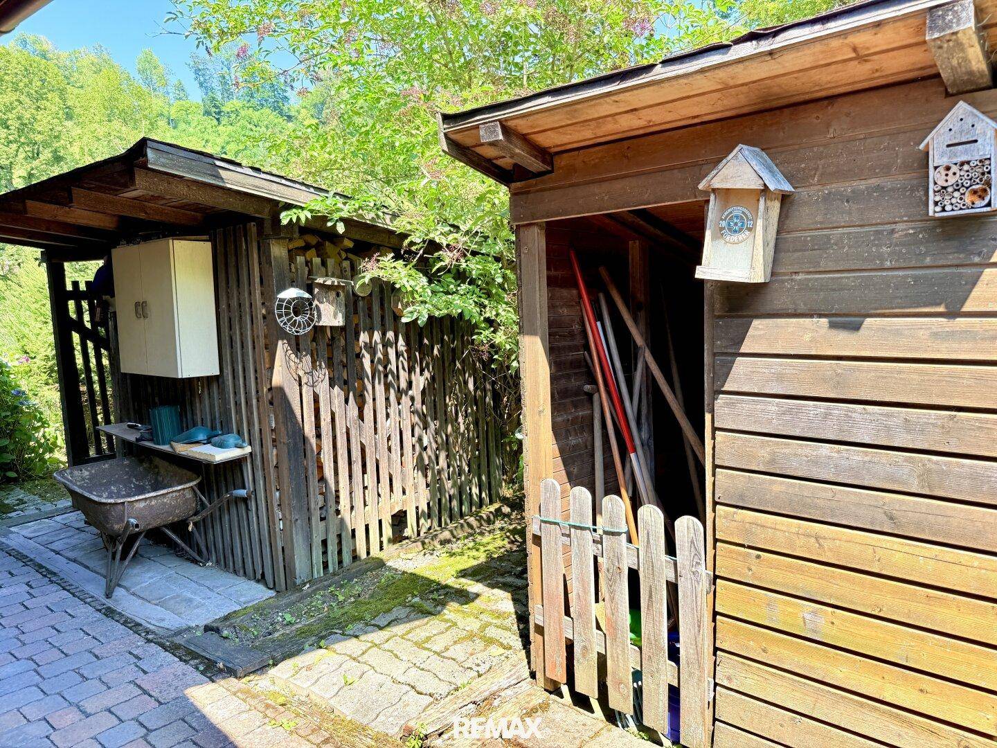 Zwei rustikale Holzschuppen im Garten, einer davon als Geräteschuppen genutzt.