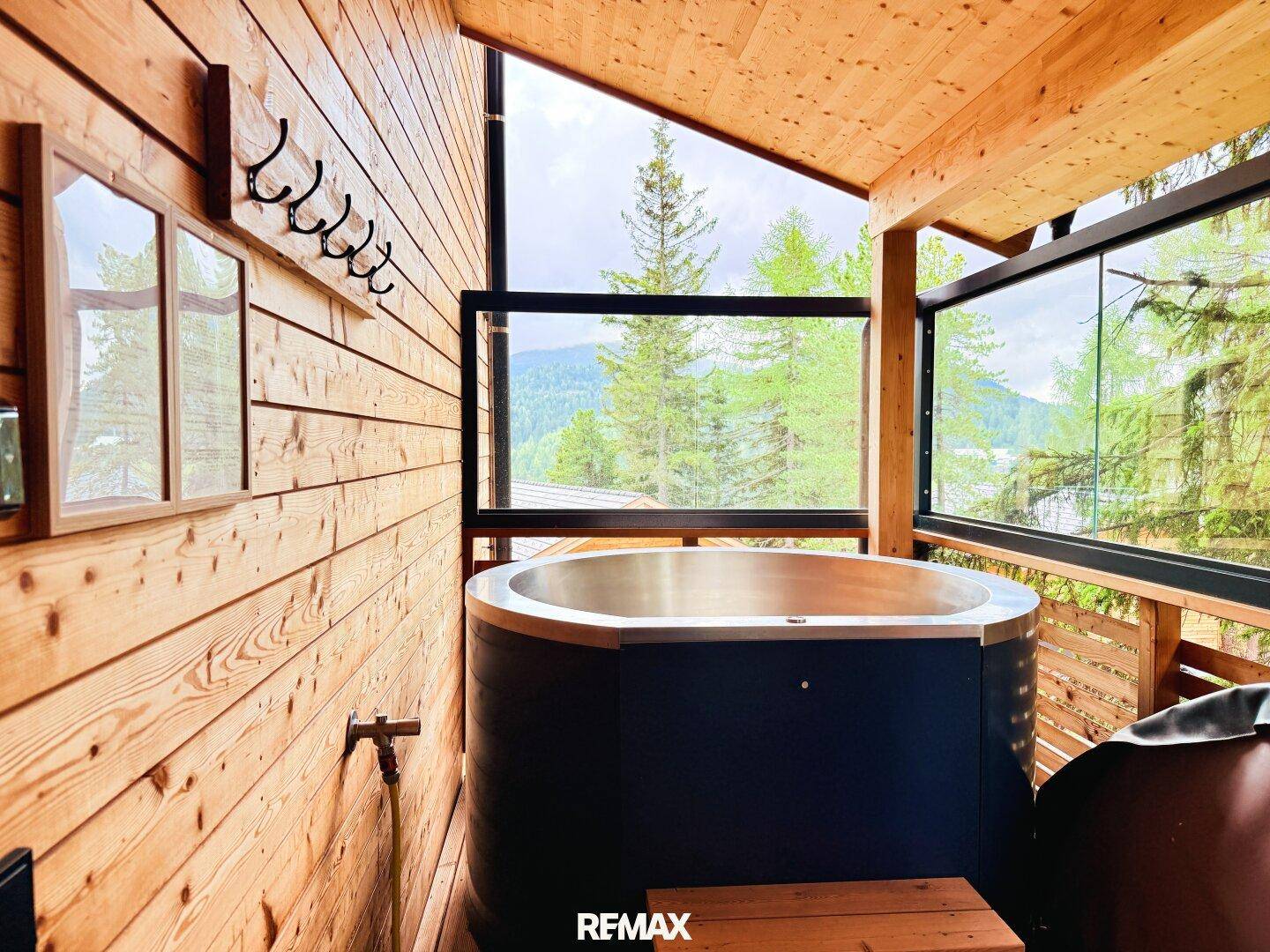 Privater Whirlpool auf dem Balkon mit Holzwänden und Panoramablick auf die Berge.